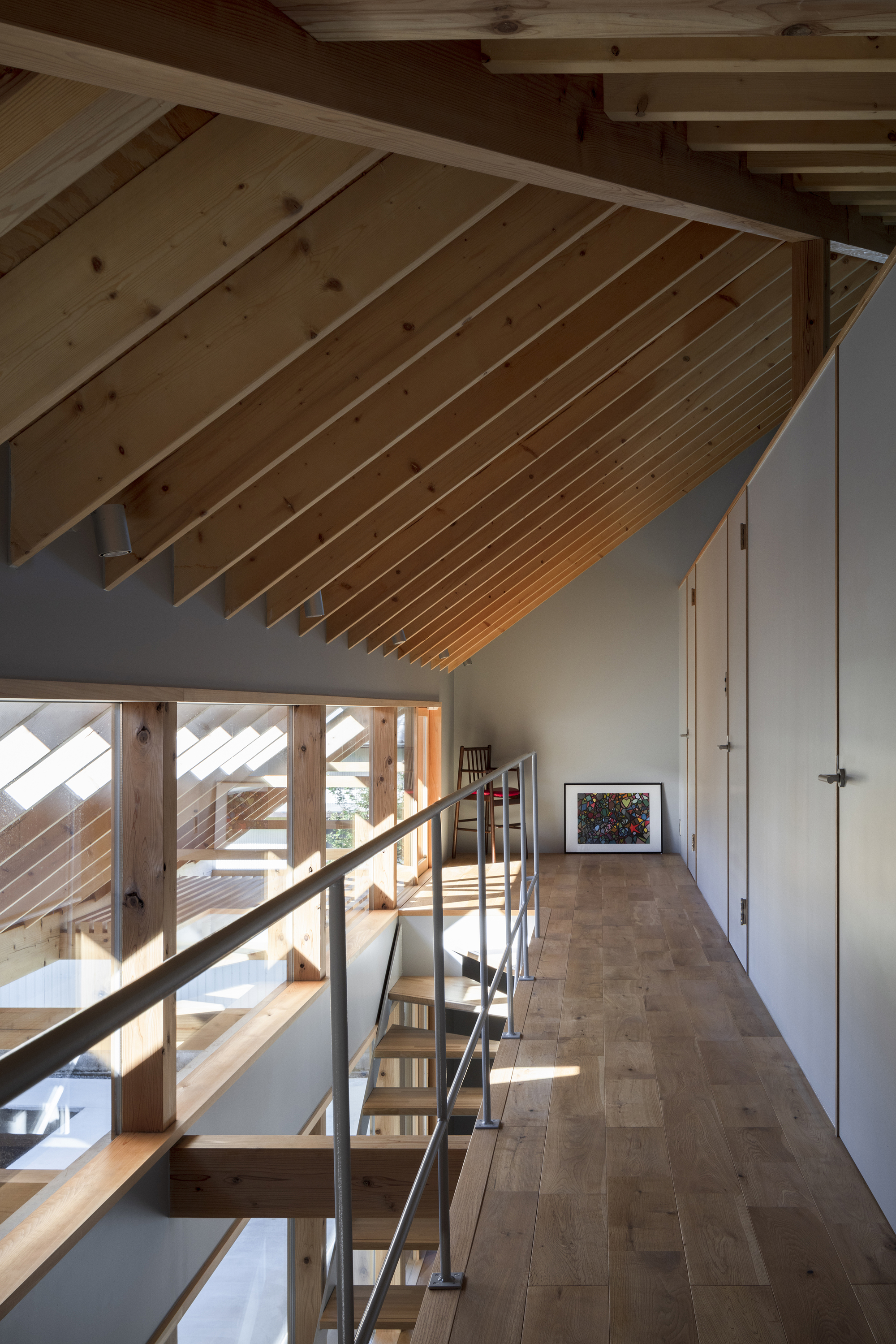Mezzanine corridor with sloped timber ceiling and steel handrail along the open edge in morning light