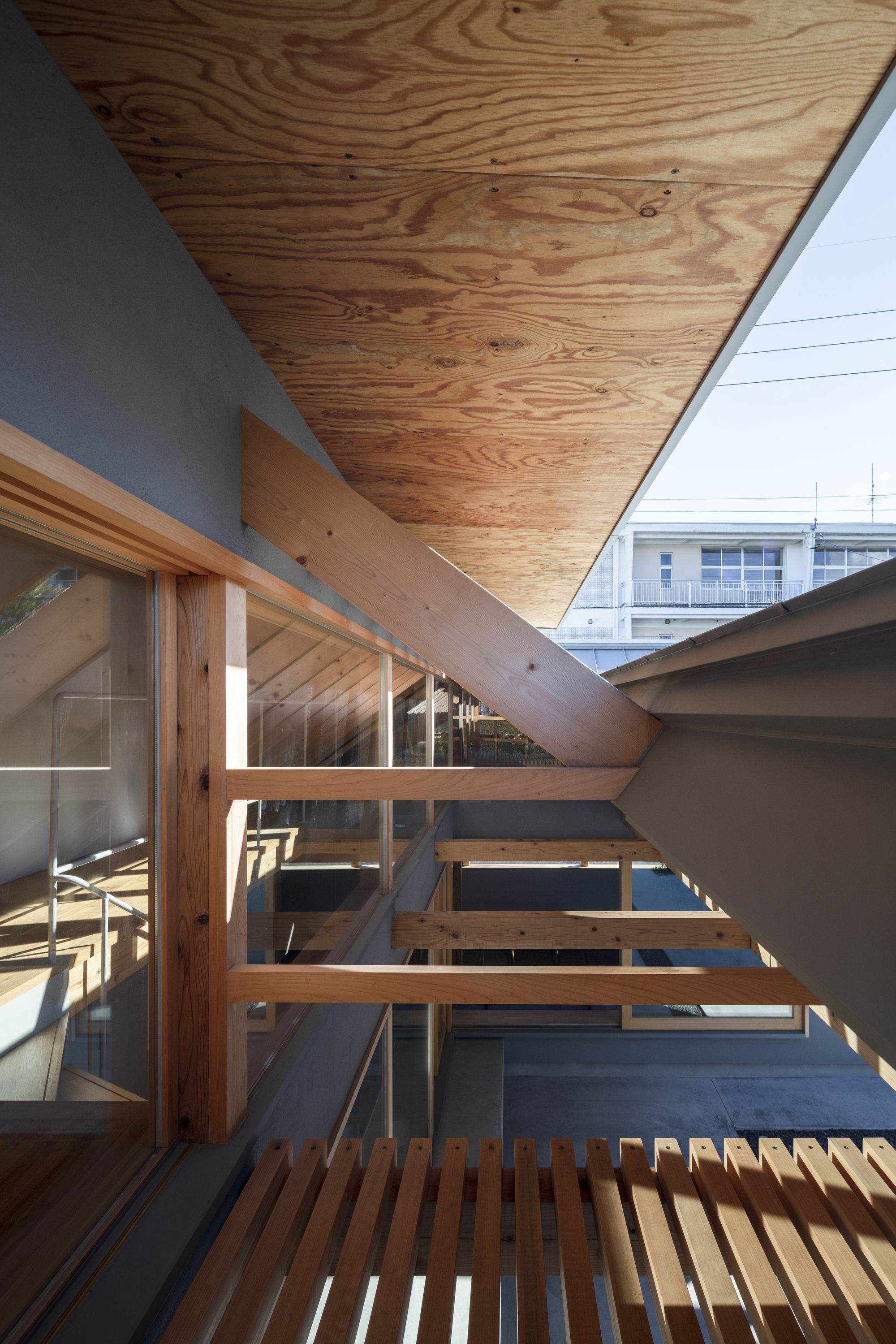 Exterior timber deck with slatted walkway and plywood soffit under bright blue sky