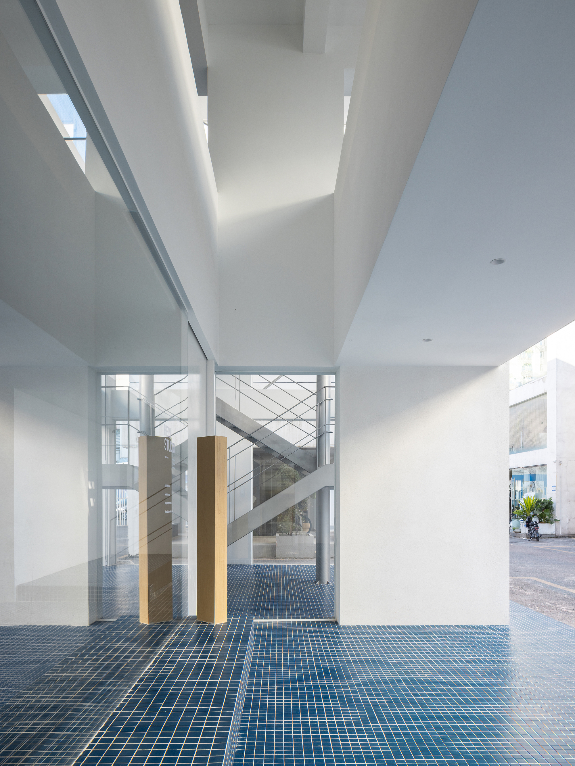 View through glass walls toward internal staircase framed by timber columns and white ceiling beams