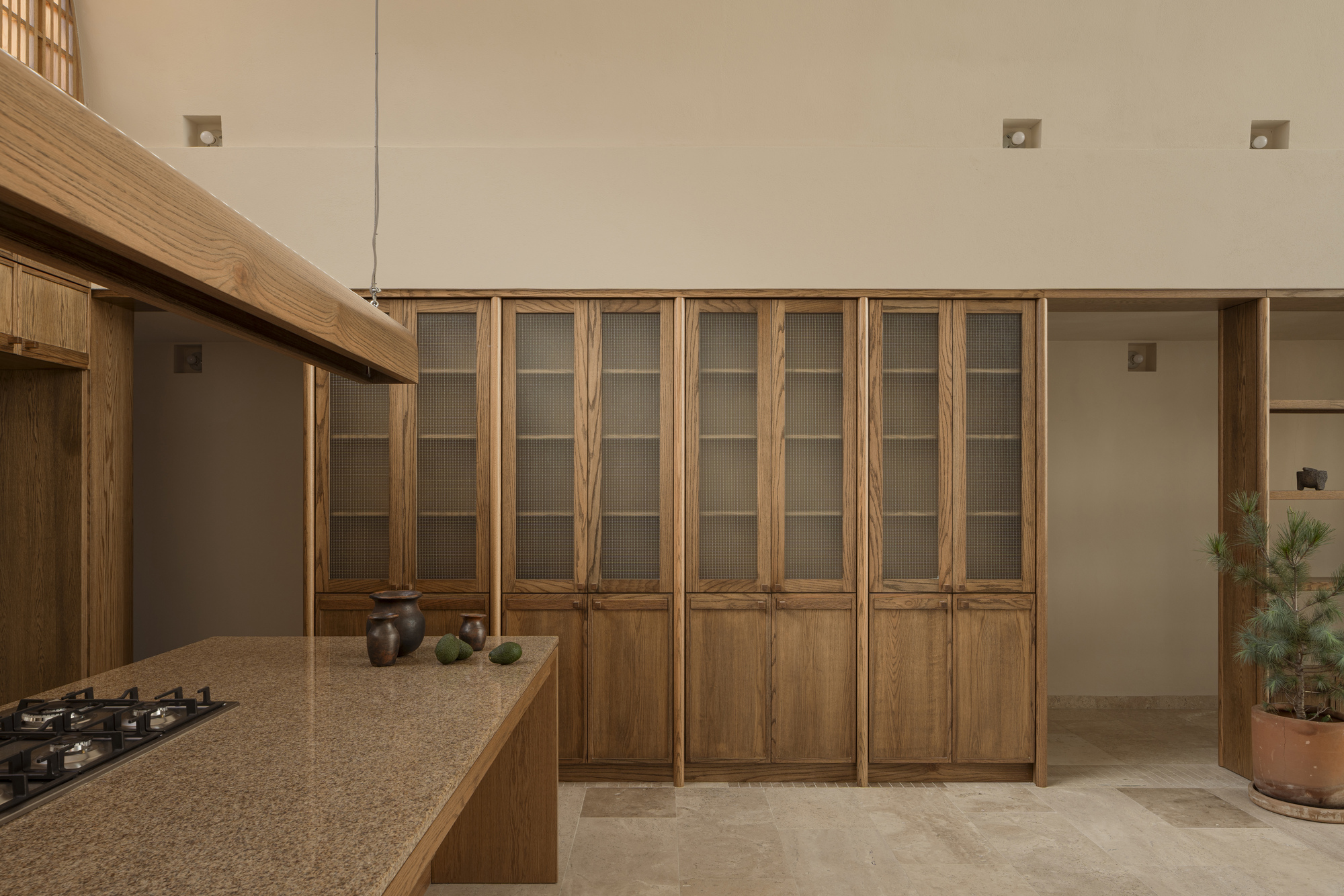 Wooden cabinetry with glass-paneled upper doors flanking a kitchen island with stone countertop