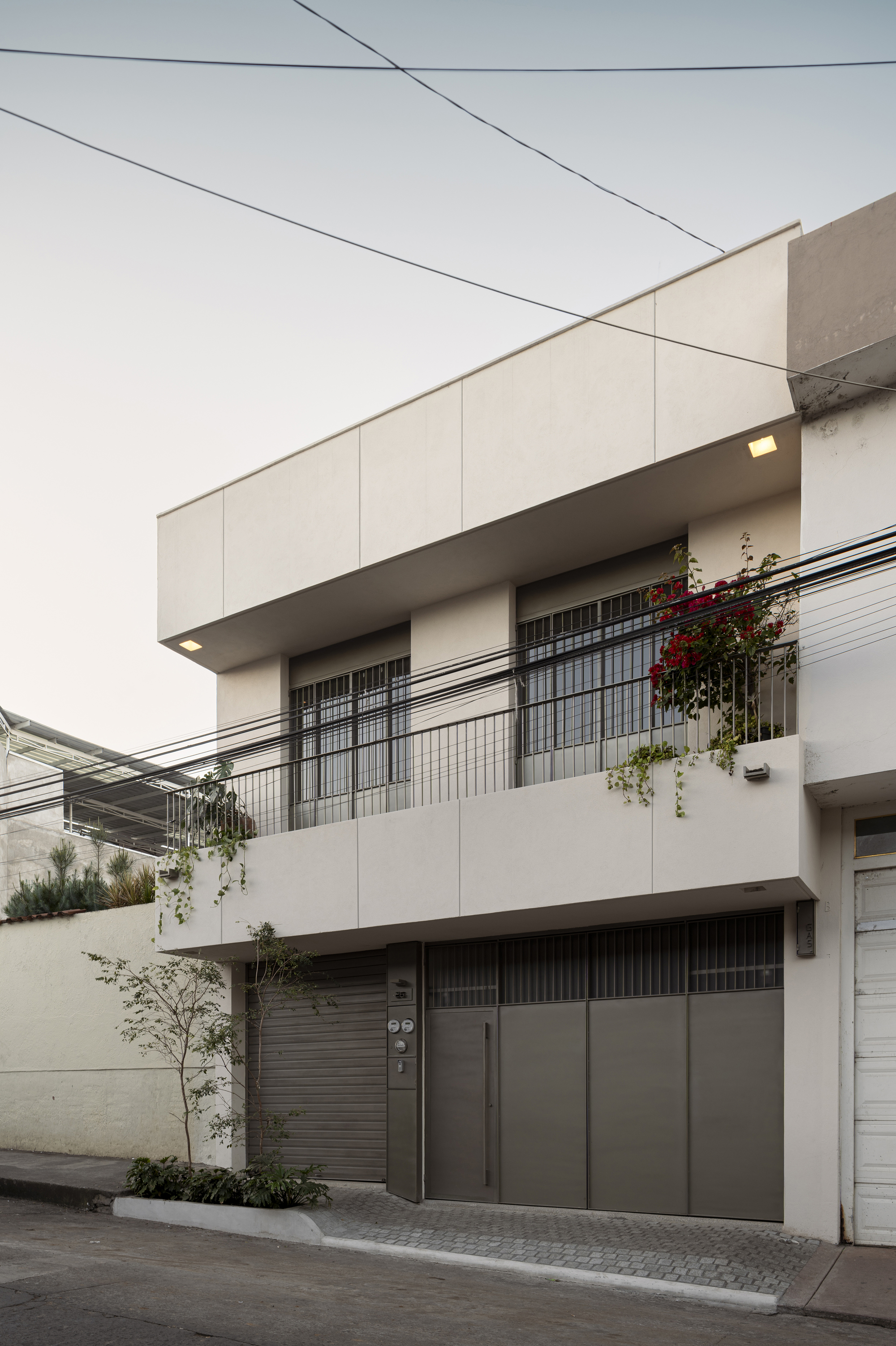 Three-story street elevation showing glass block windows, planted balconies, and overhead utility wires