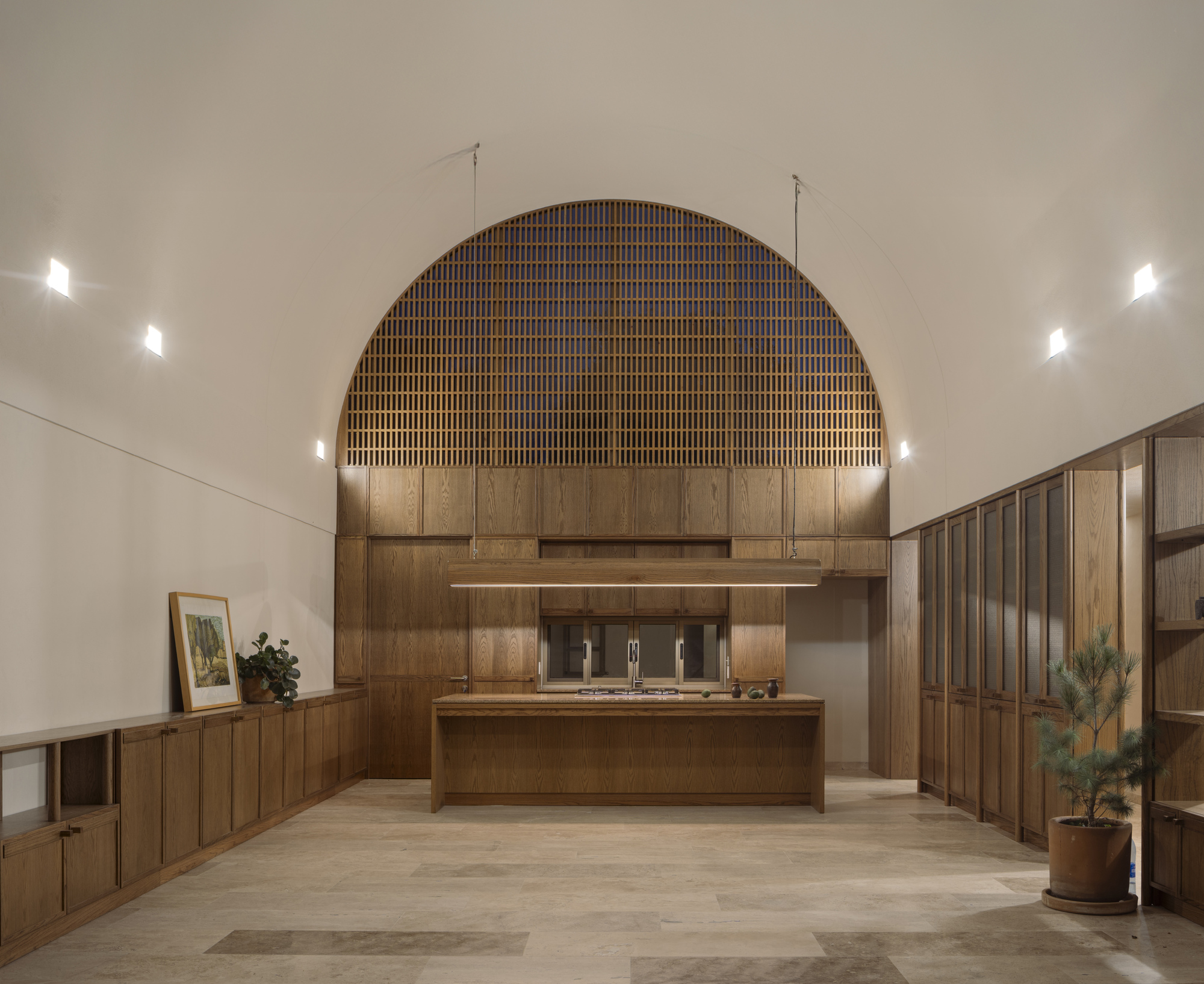 Kitchen island under a vaulted ceiling with timber slat arch and recessed wall lighting