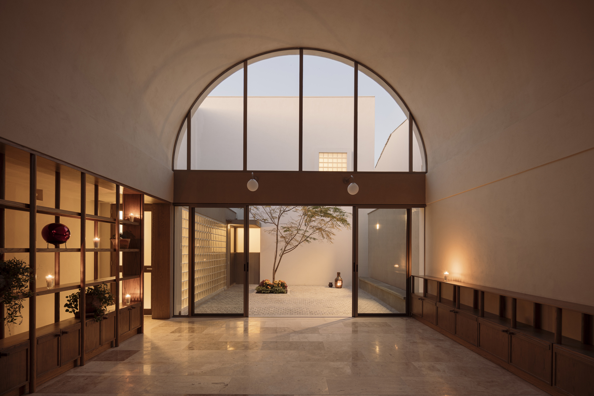 Entry hall looking through an arched opening to a glass block courtyard wall at dusk
