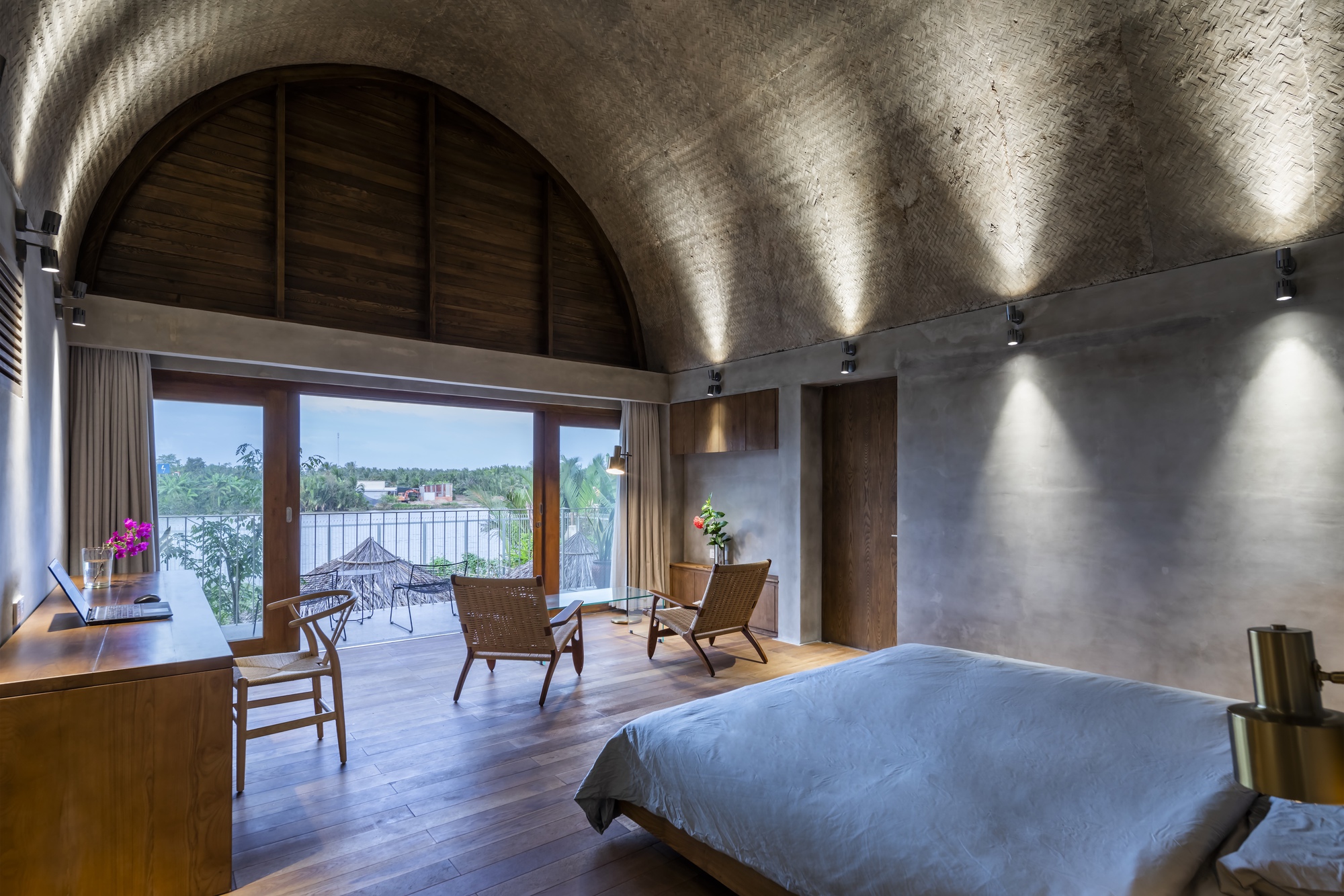 Bedroom with barrel vaulted concrete ceiling and timber-framed doors opening to a lakeside terrace