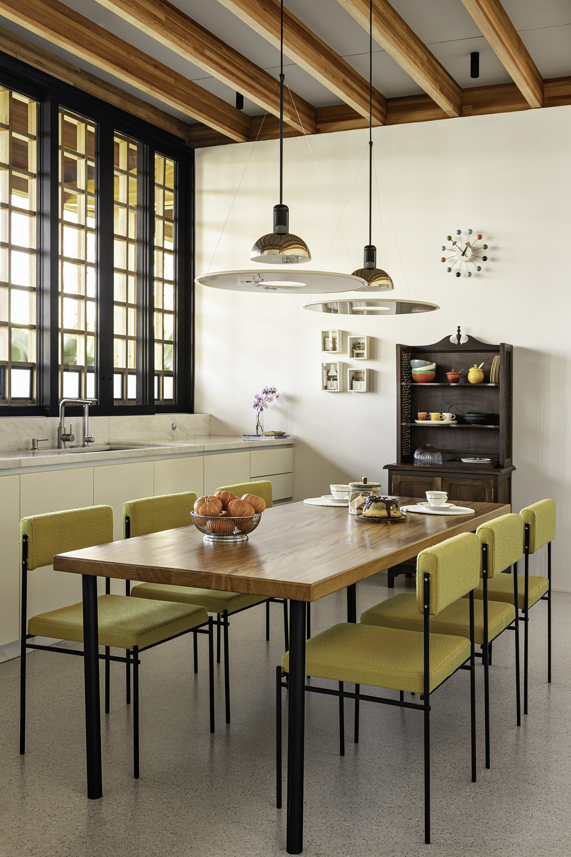 Dining area with timber table, olive upholstered chairs and dark gridded windows under exposed beam ceiling