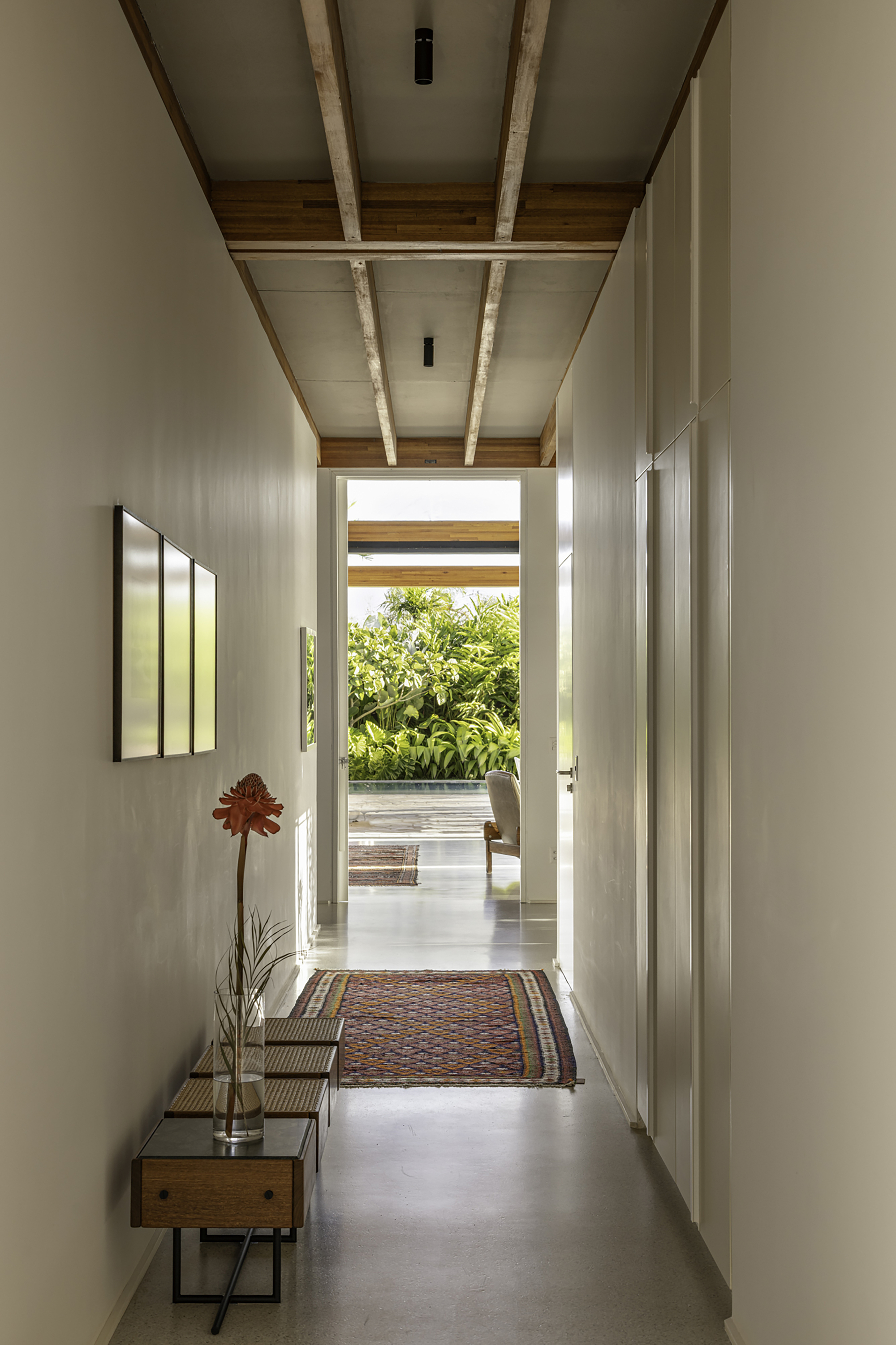 Hallway with timber and white panel ceiling leading to a terrace with tropical foliage beyond