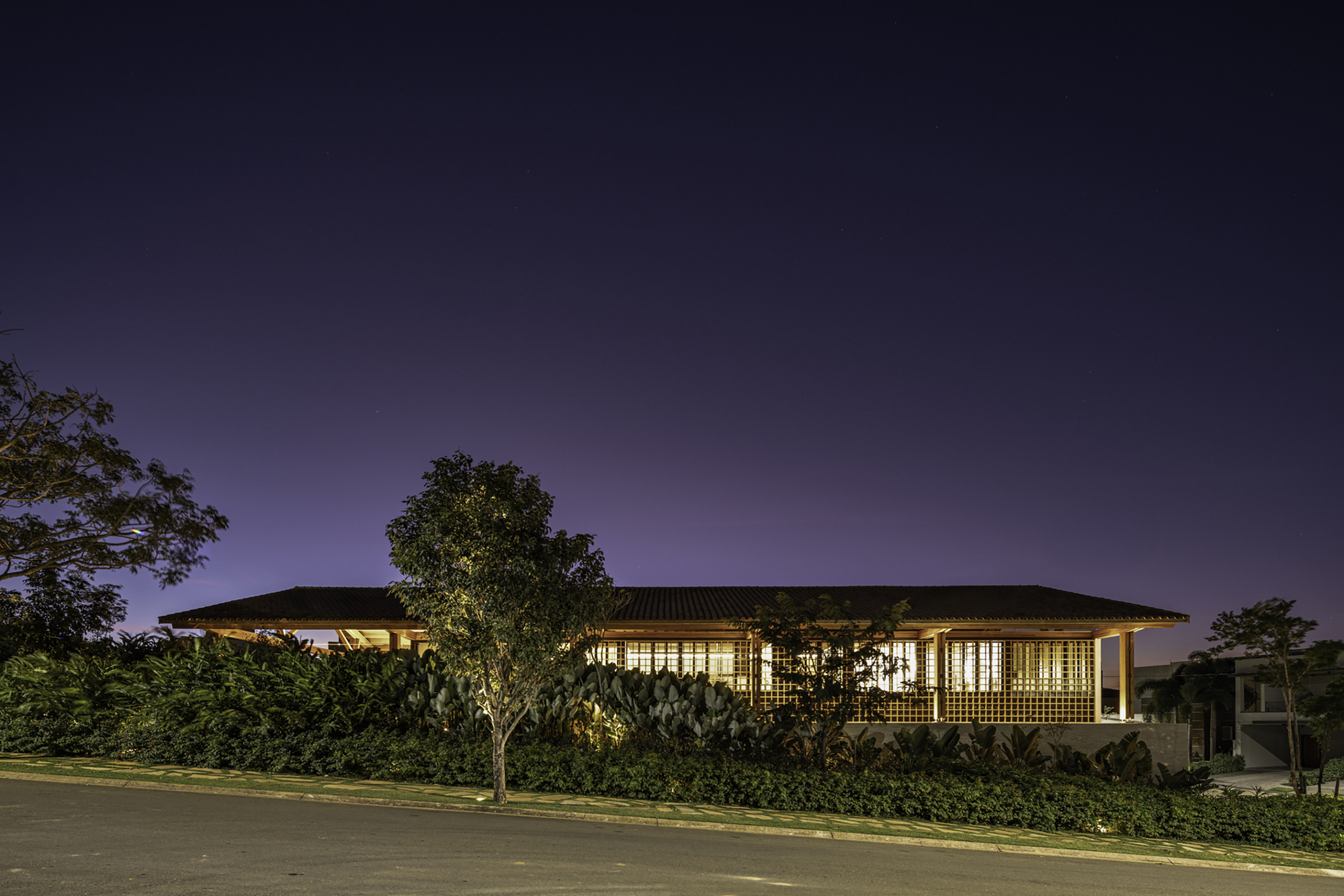 Street view of the illuminated glazed facade and low-pitched roof at night