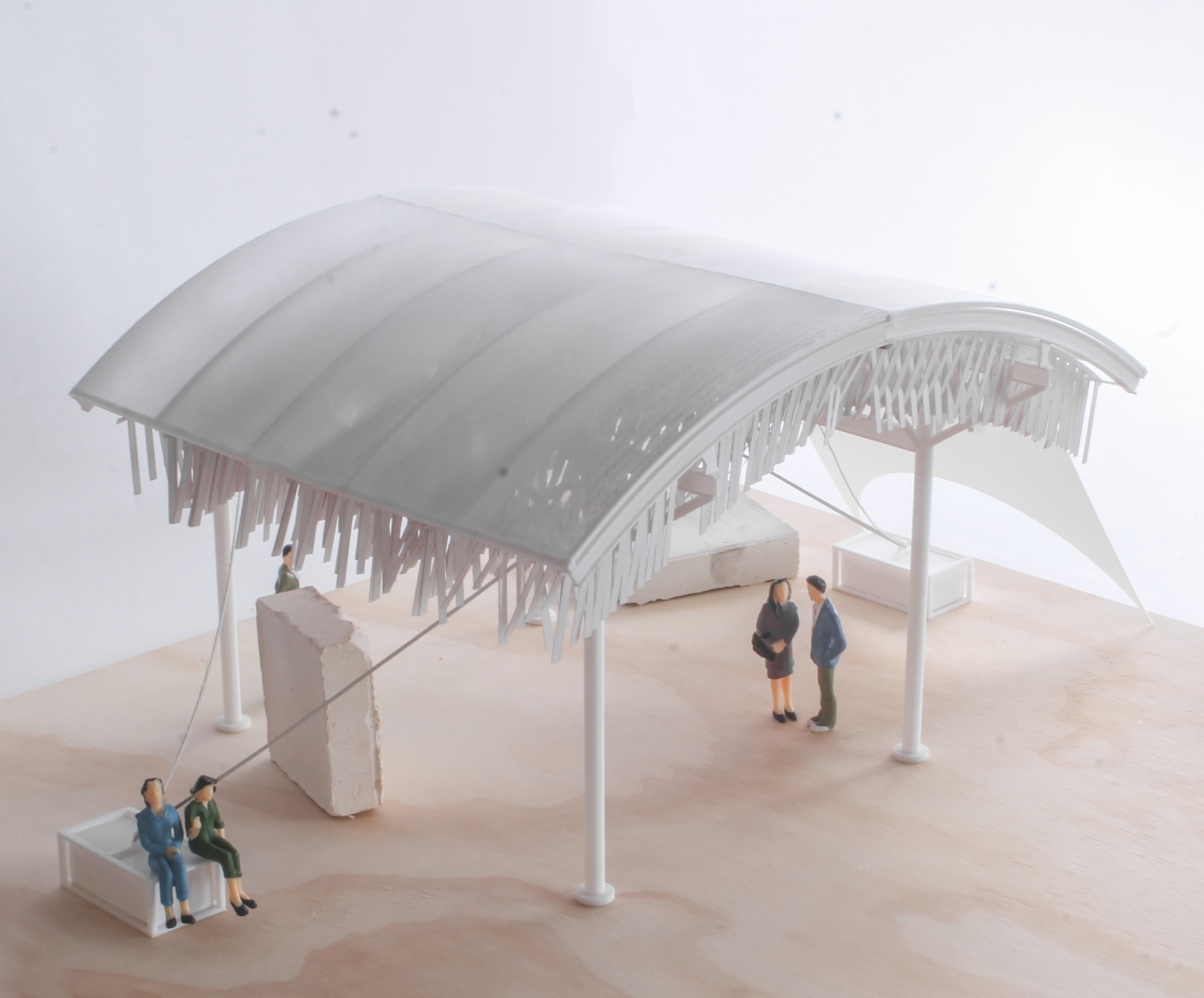 Physical model of the curved roof canopy with white columns, icicle-like elements, and miniature figures on a base