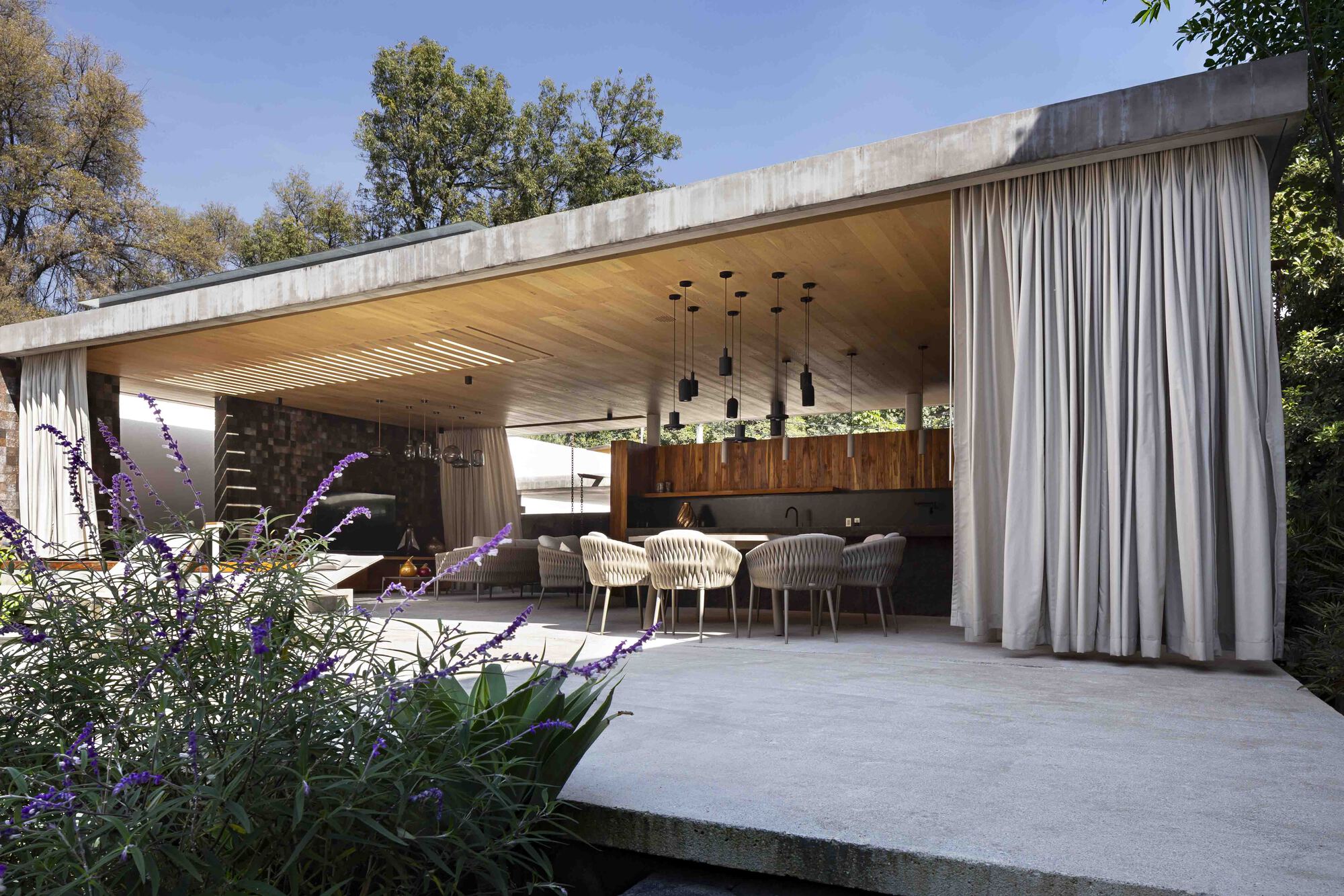 The pavilion seen from the garden with linen curtains framing the dining area