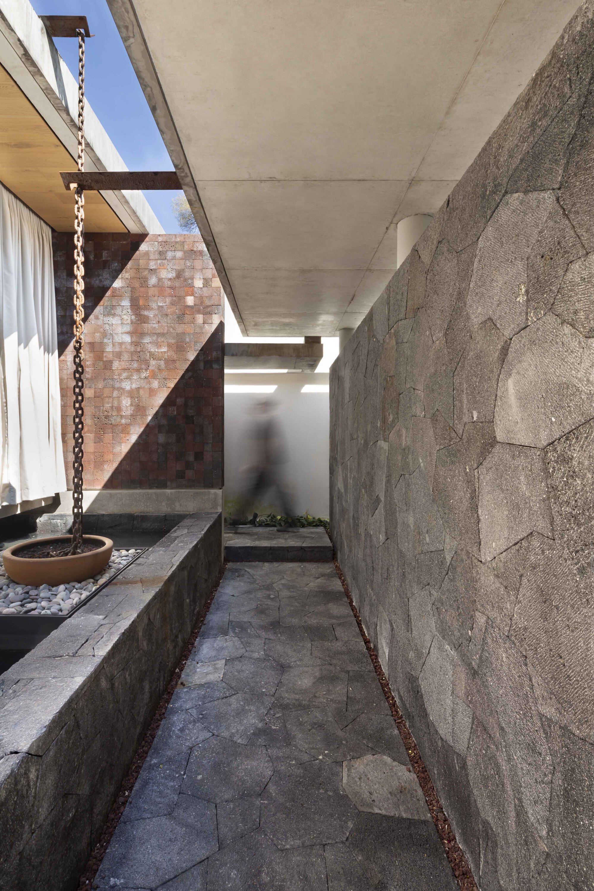 Narrow side passage with stone-clad wall and a stone-floor path leading to the rear