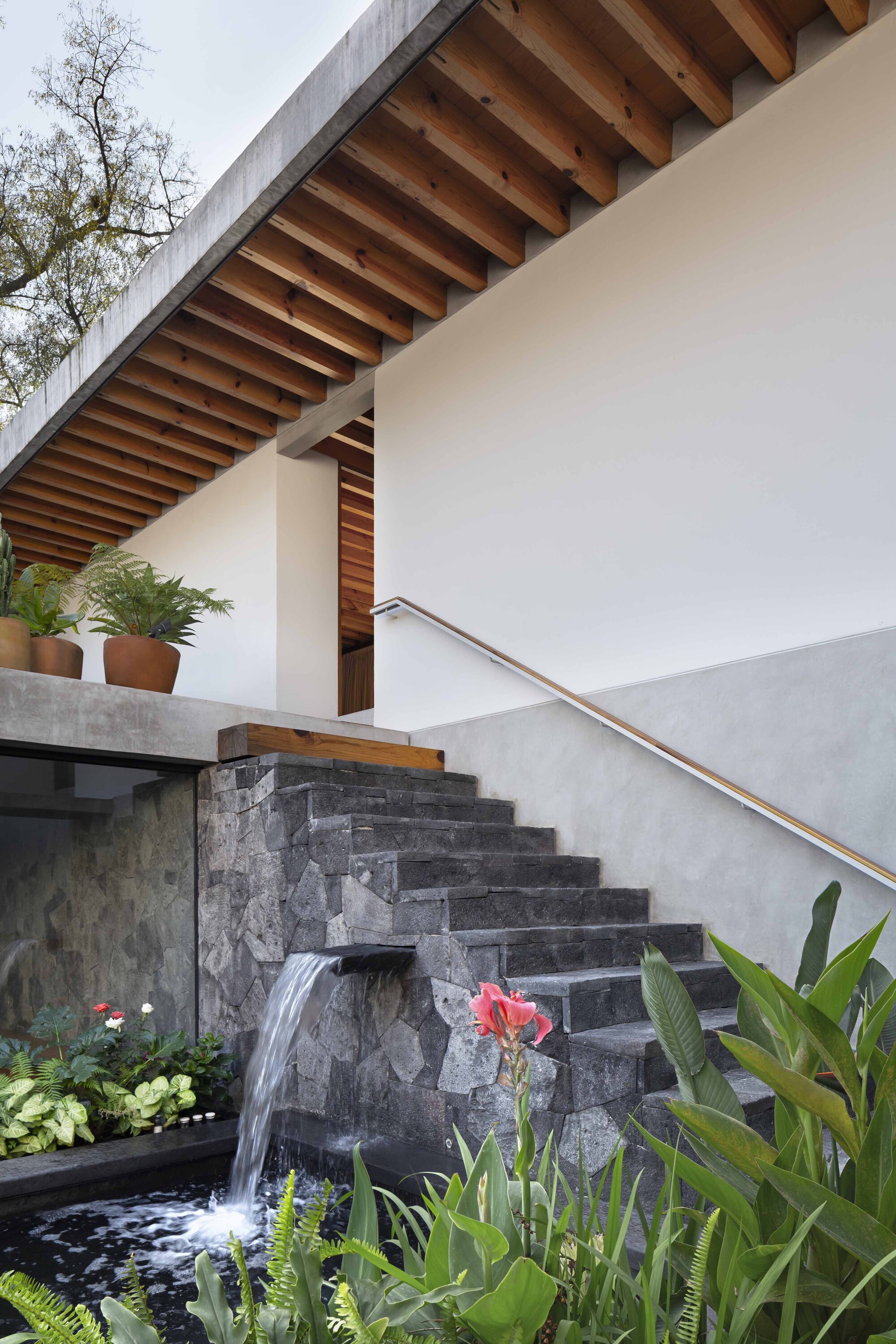 Stone stair with a small water cascade beside it and an exposed timber soffit above