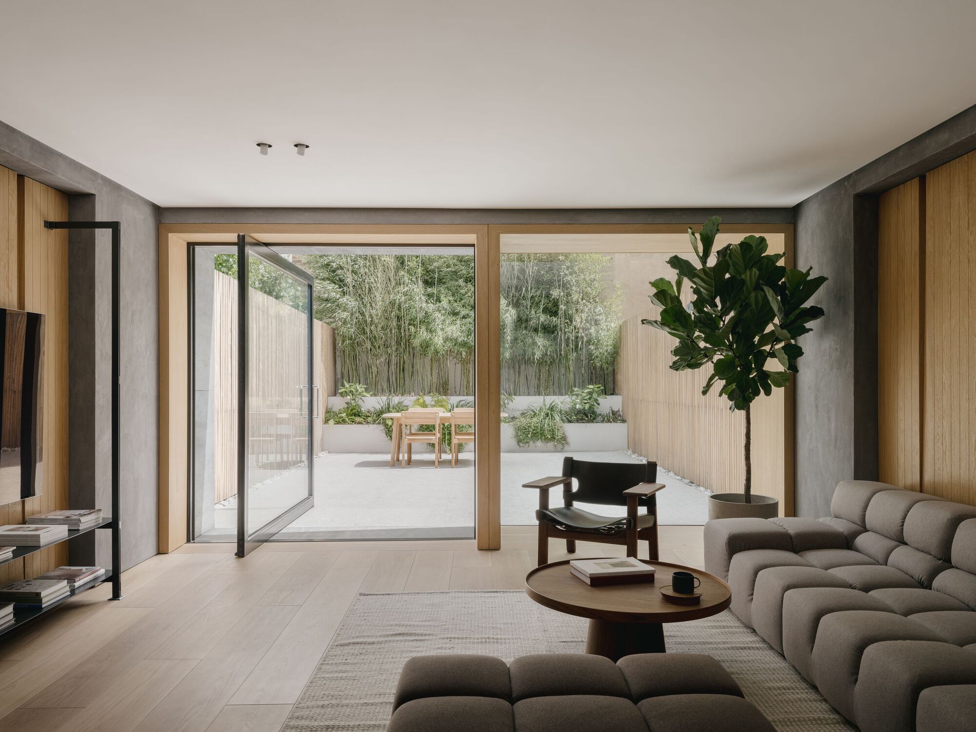 Living room with timber-framed sliding doors opening to a courtyard with bamboo and timber fence