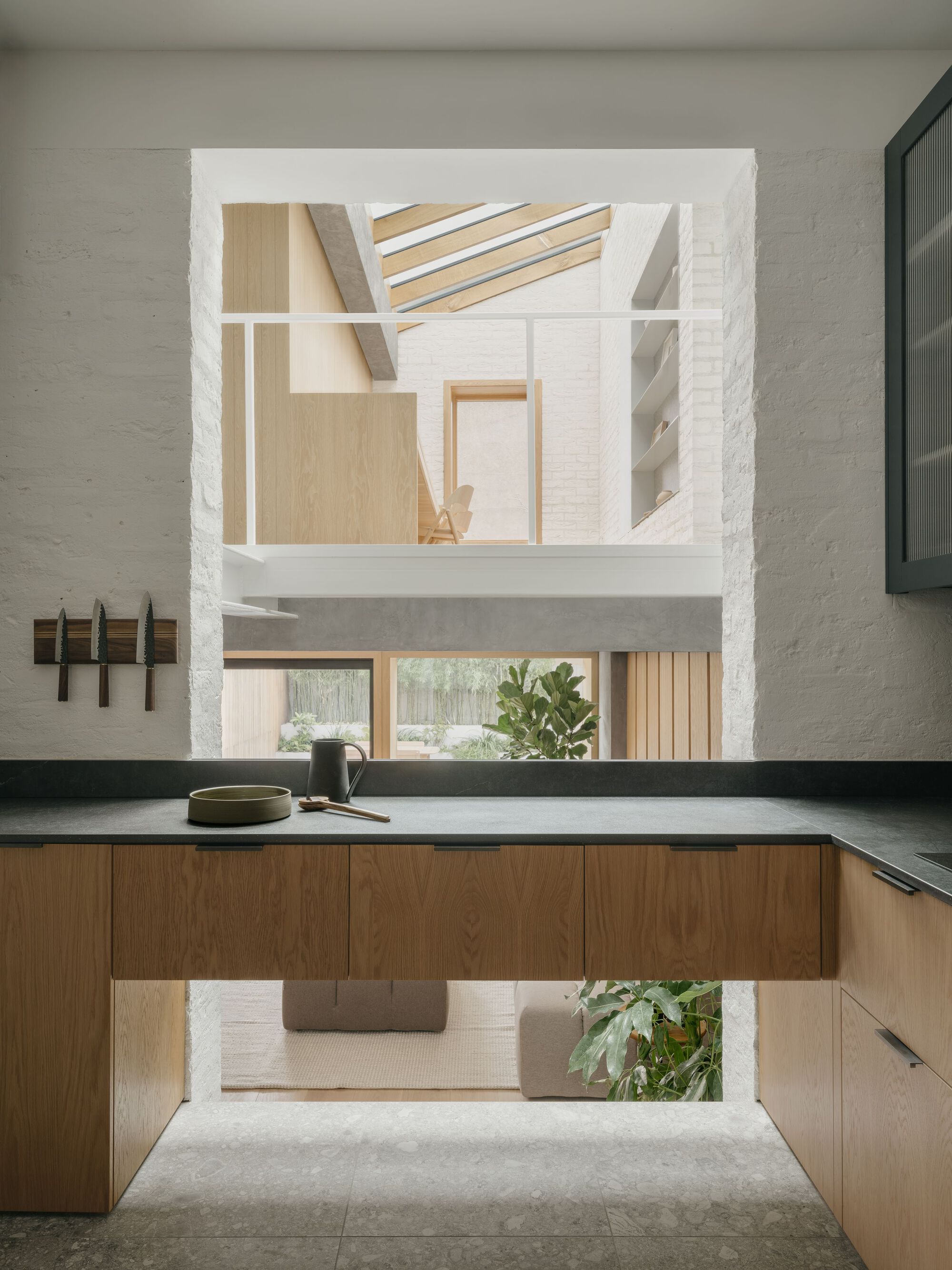 Kitchen island with dark countertop framing views through a vertical opening to the upper level