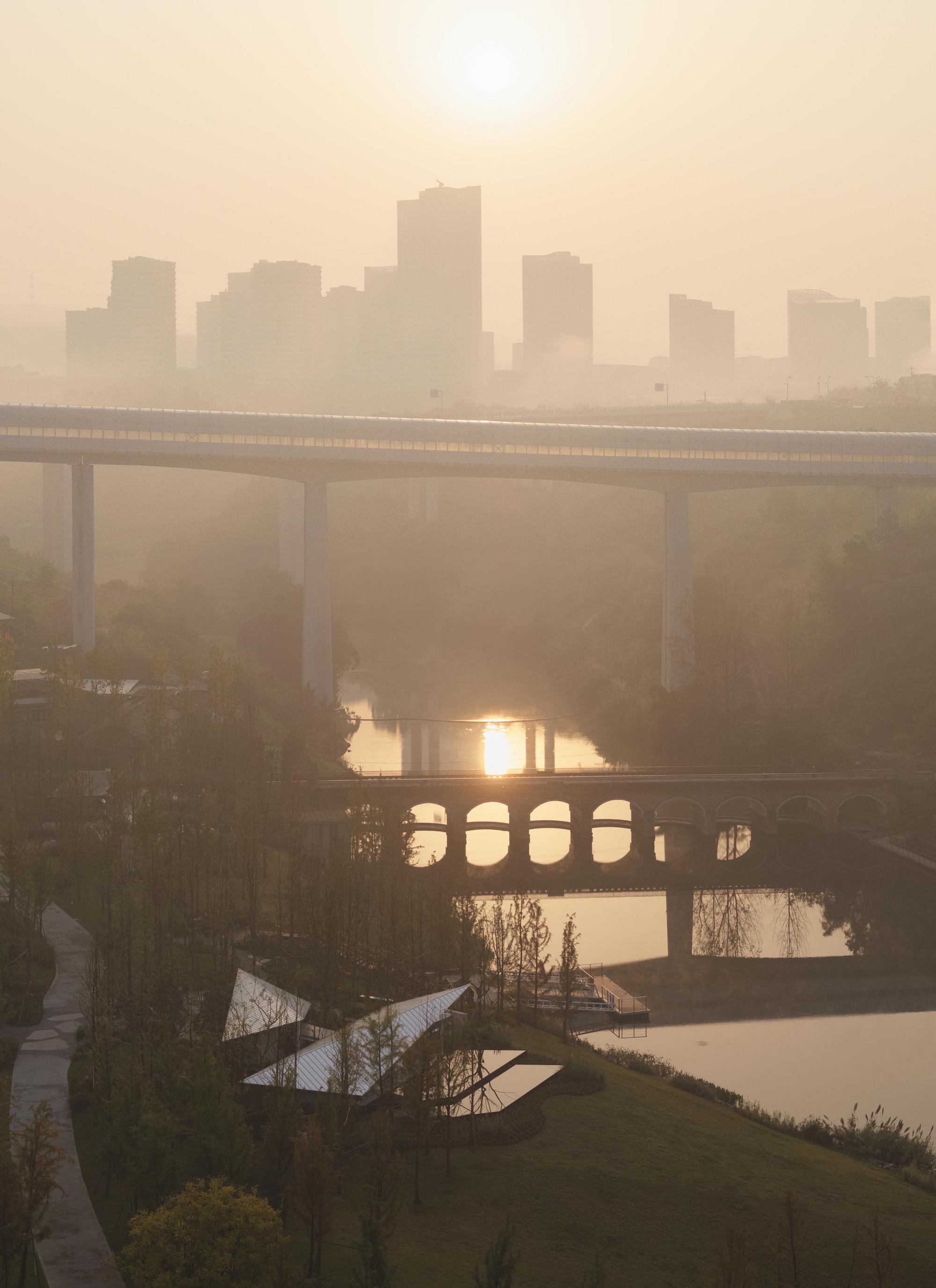 Layered bridges crossing a river with distant skyline silhouettes in heavy morning haze