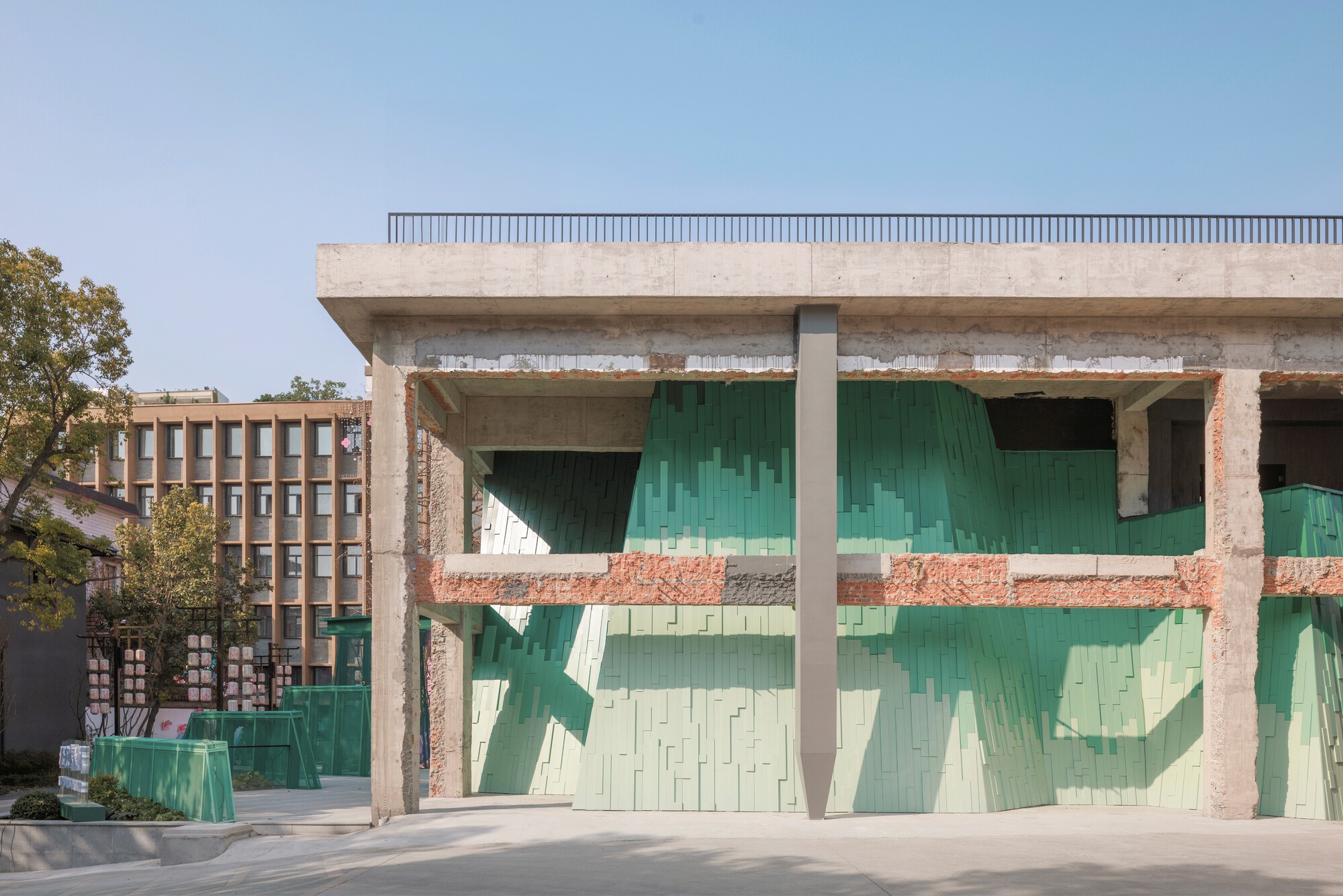 Covered loggia with gradient green tile infill panels set within an exposed concrete structure