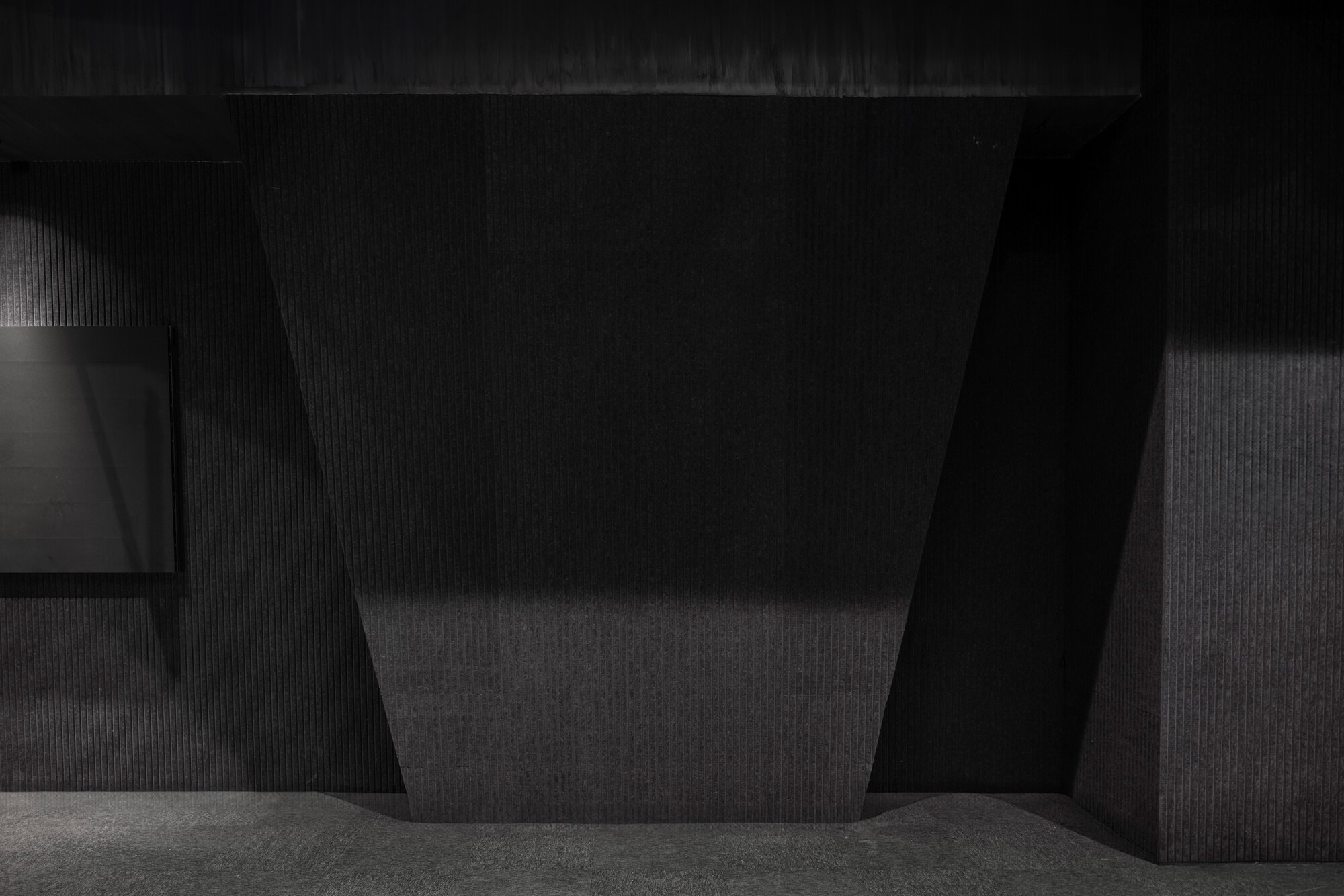 Interior corner showing a tapered dark column against ribbed wall surfaces in low light