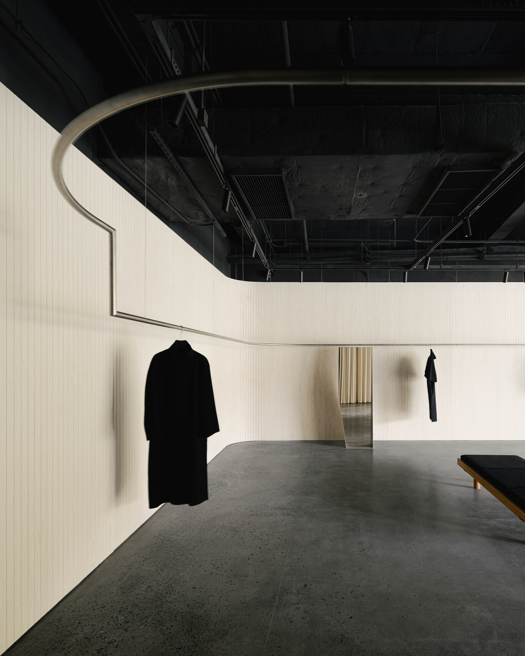 Curved opening in a ribbed cream wall revealing a glimpse through to a courtyard beyond