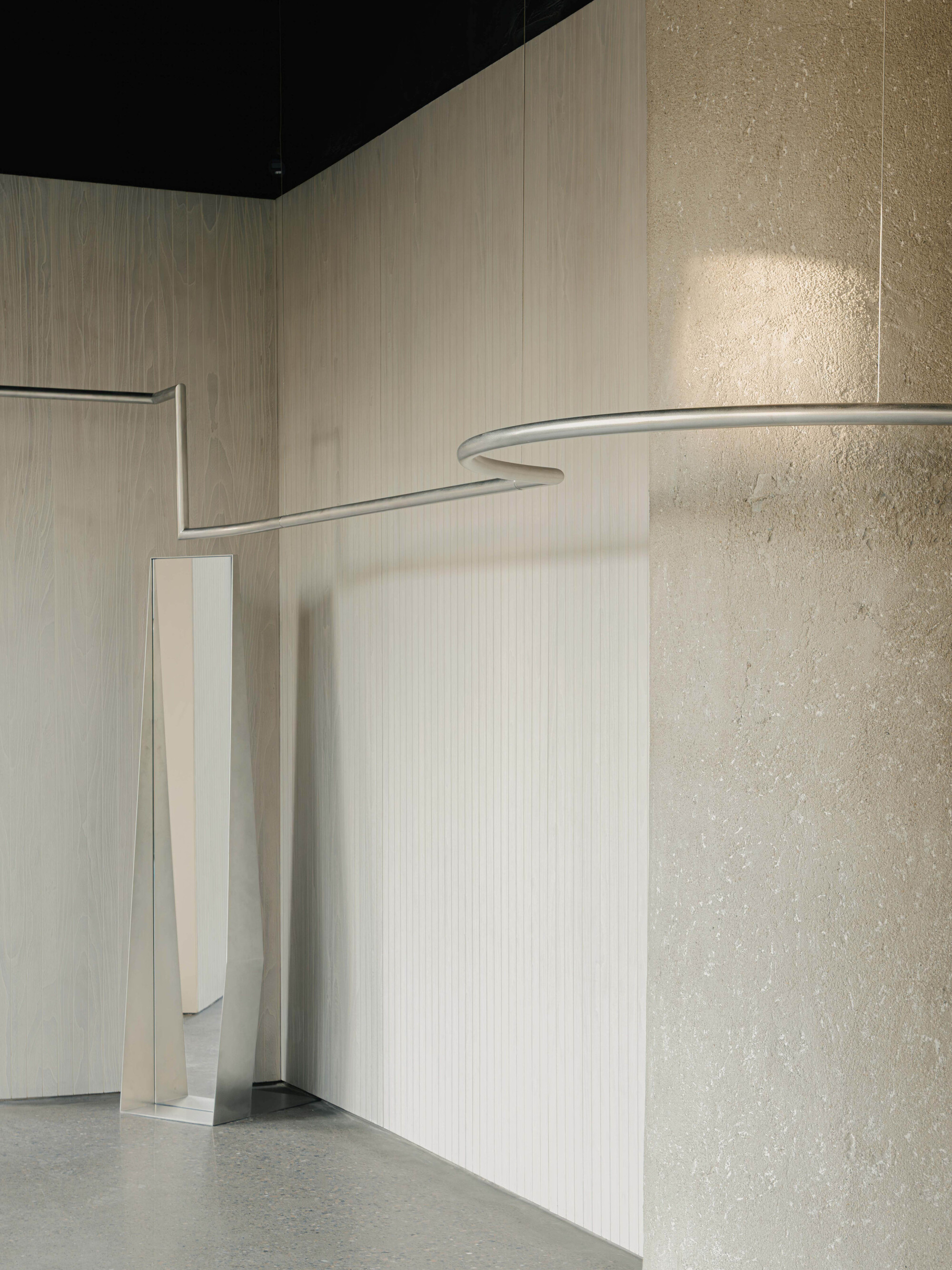 Narrow vertical slot in a pale paneled wall adjacent to a textured plaster column