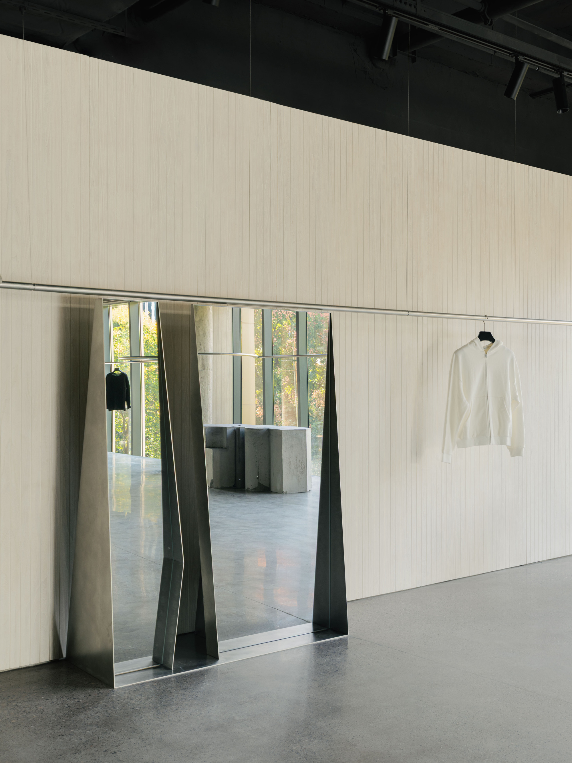Trapezoidal doorway with folded metal jambs framing view into adjacent room with concrete columns