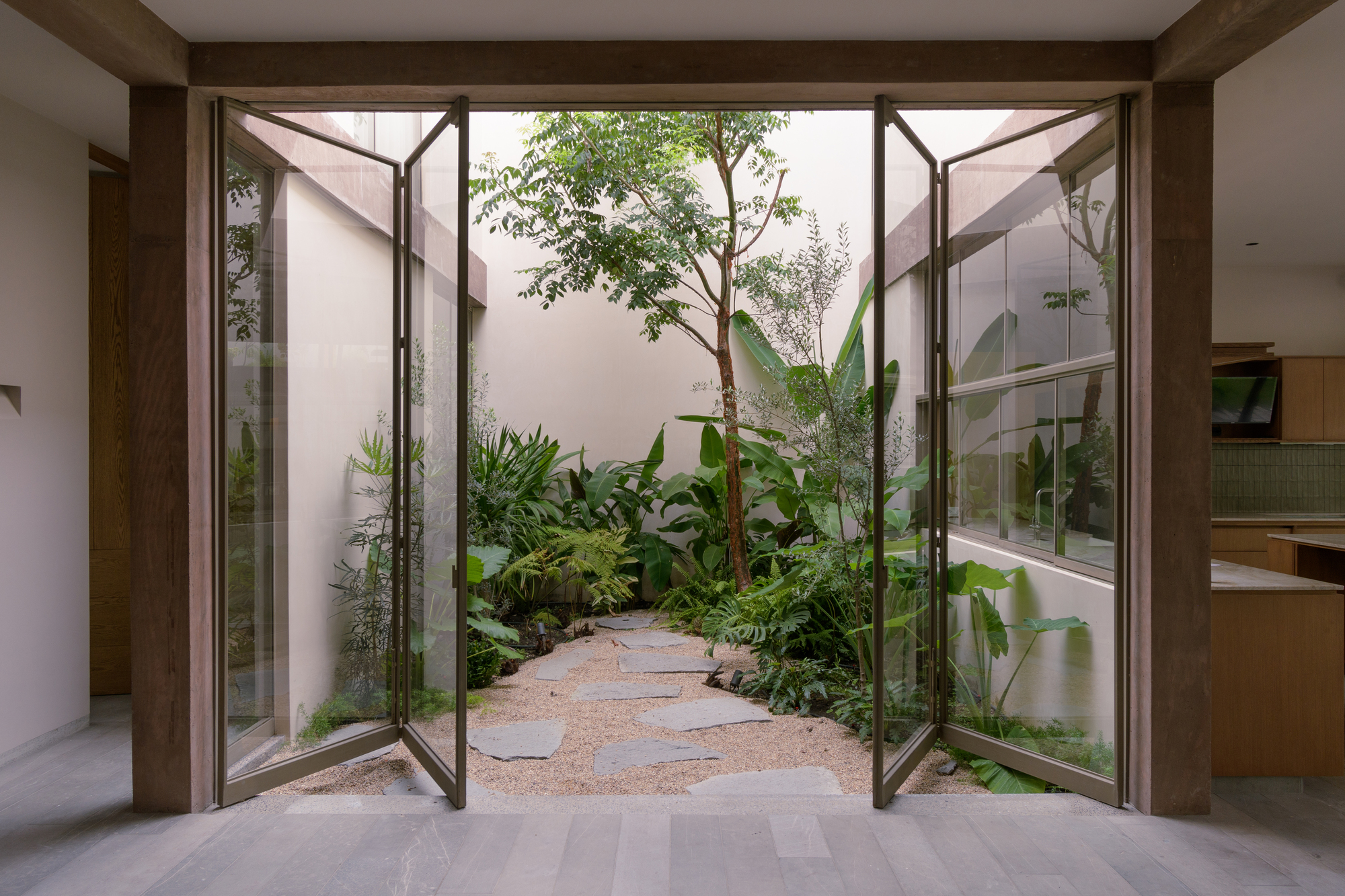 Open timber-framed glass doors leading to internal courtyard garden with stepping stones and tropical planting