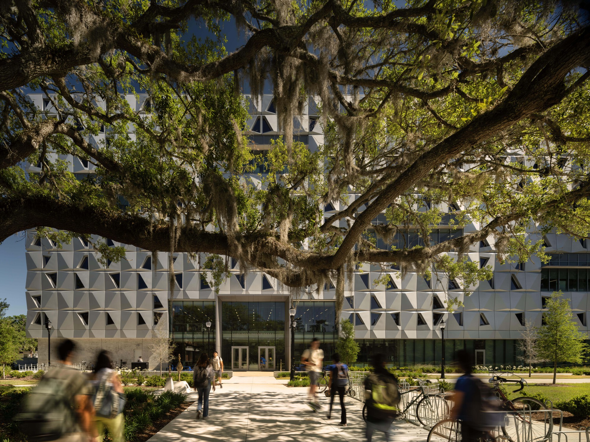 Entry facade with triangular relief panels framed by sprawling oak tree branches draped with Spanish moss