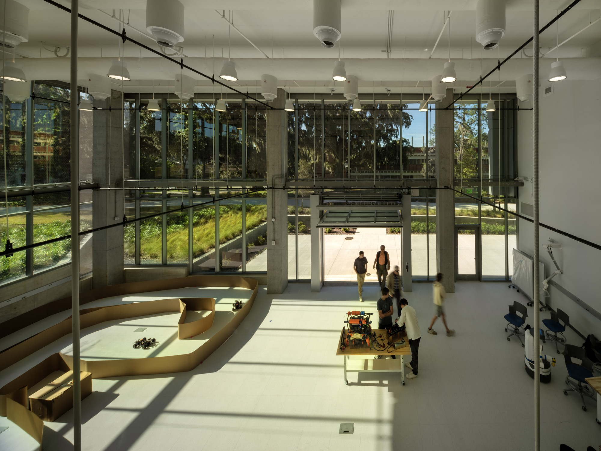 Double-height lobby with full-height glazing overlooking a planted courtyard as students gather inside