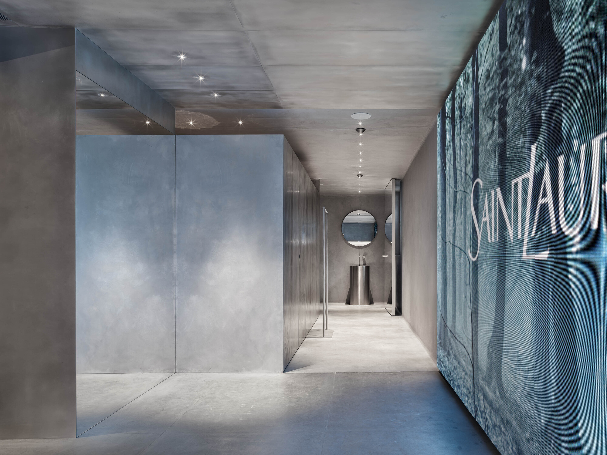 Corridor with polished concrete ceiling, recessed spotlights and graphic wall panel at the far end