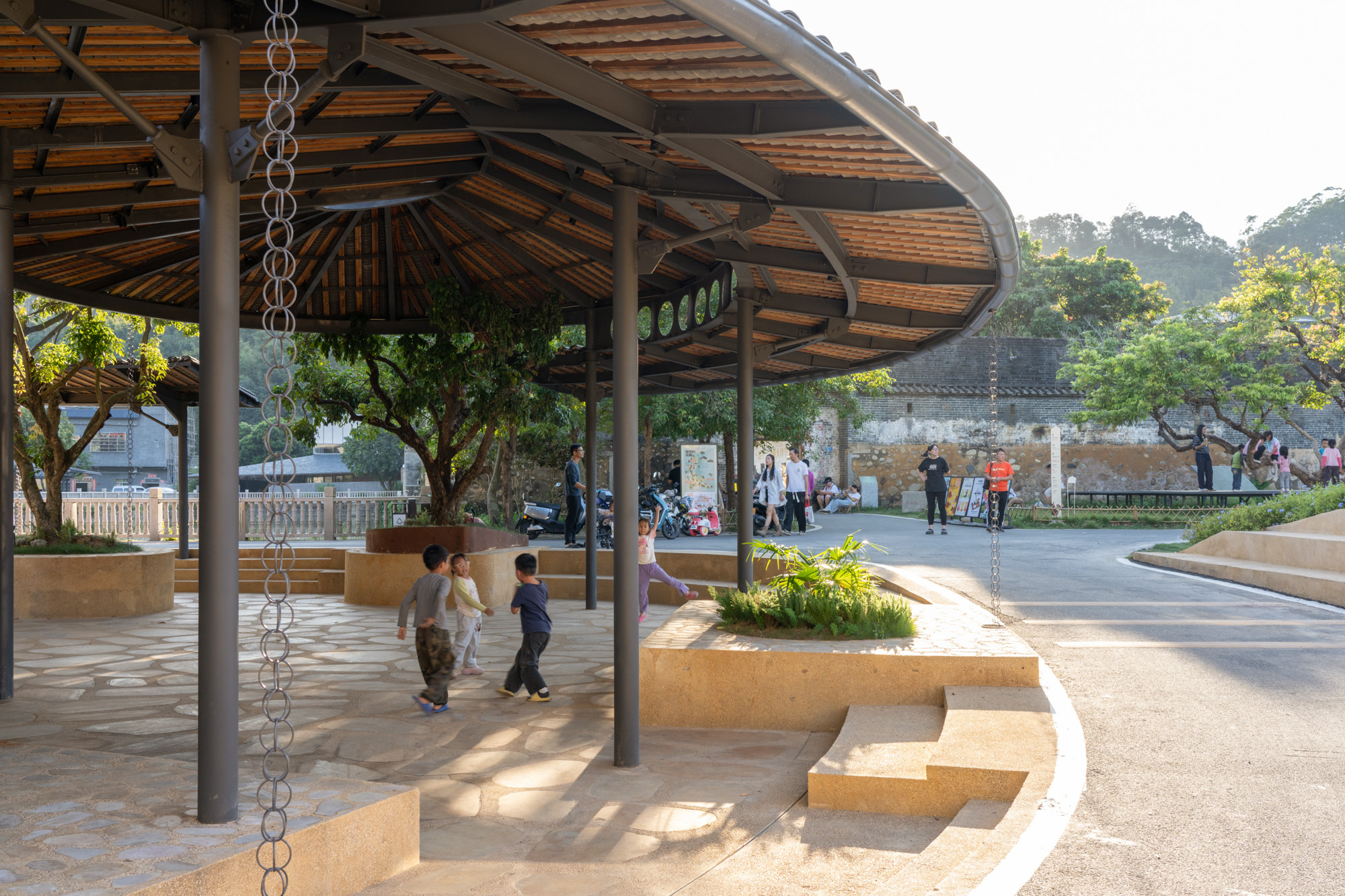 View beneath the pavilion showing stepped seating platforms and a rain chain suspended from the bamboo ceiling structure