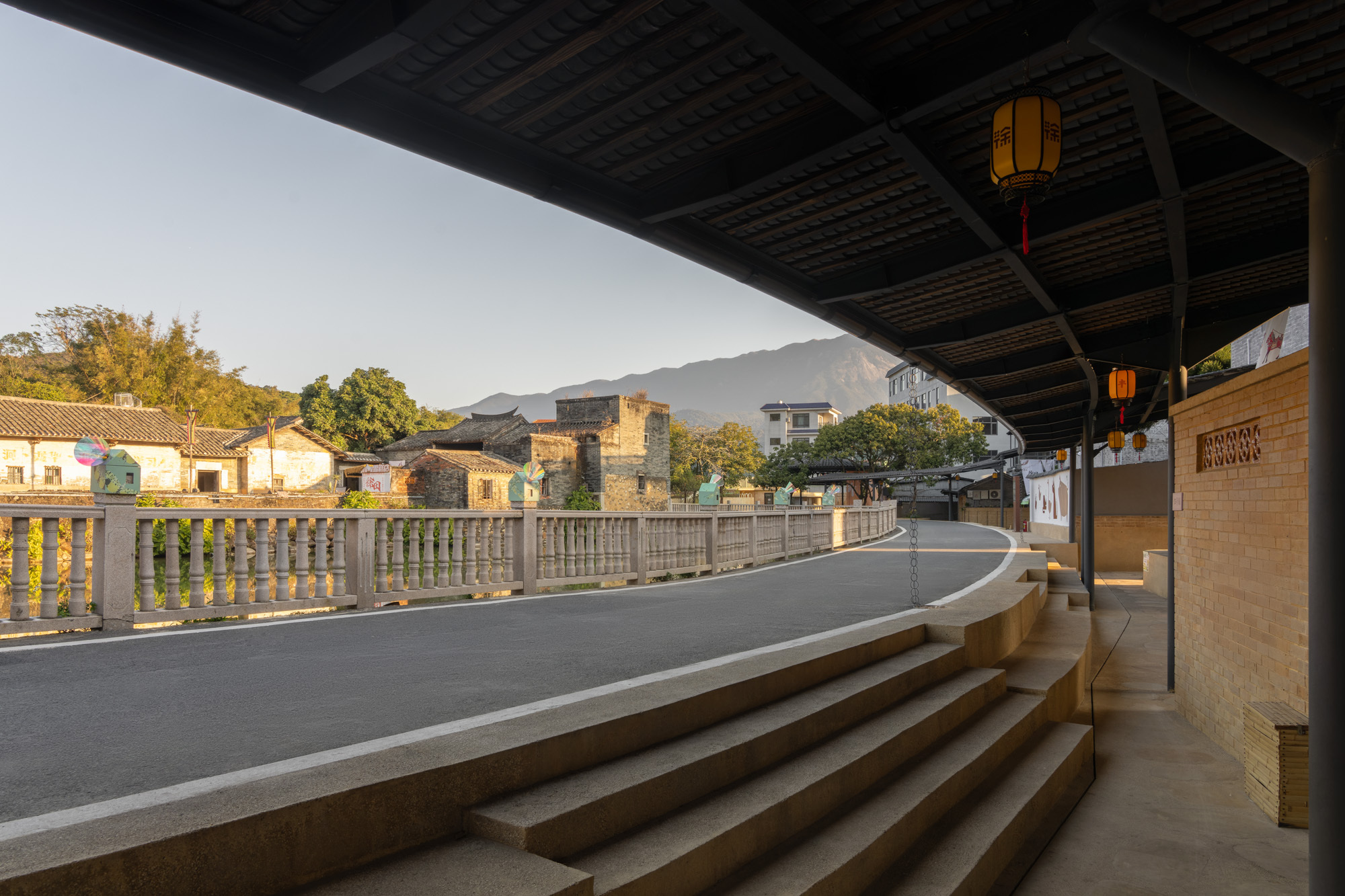 View from beneath the canopy showing terraced seating steps facing the village roadway at dusk