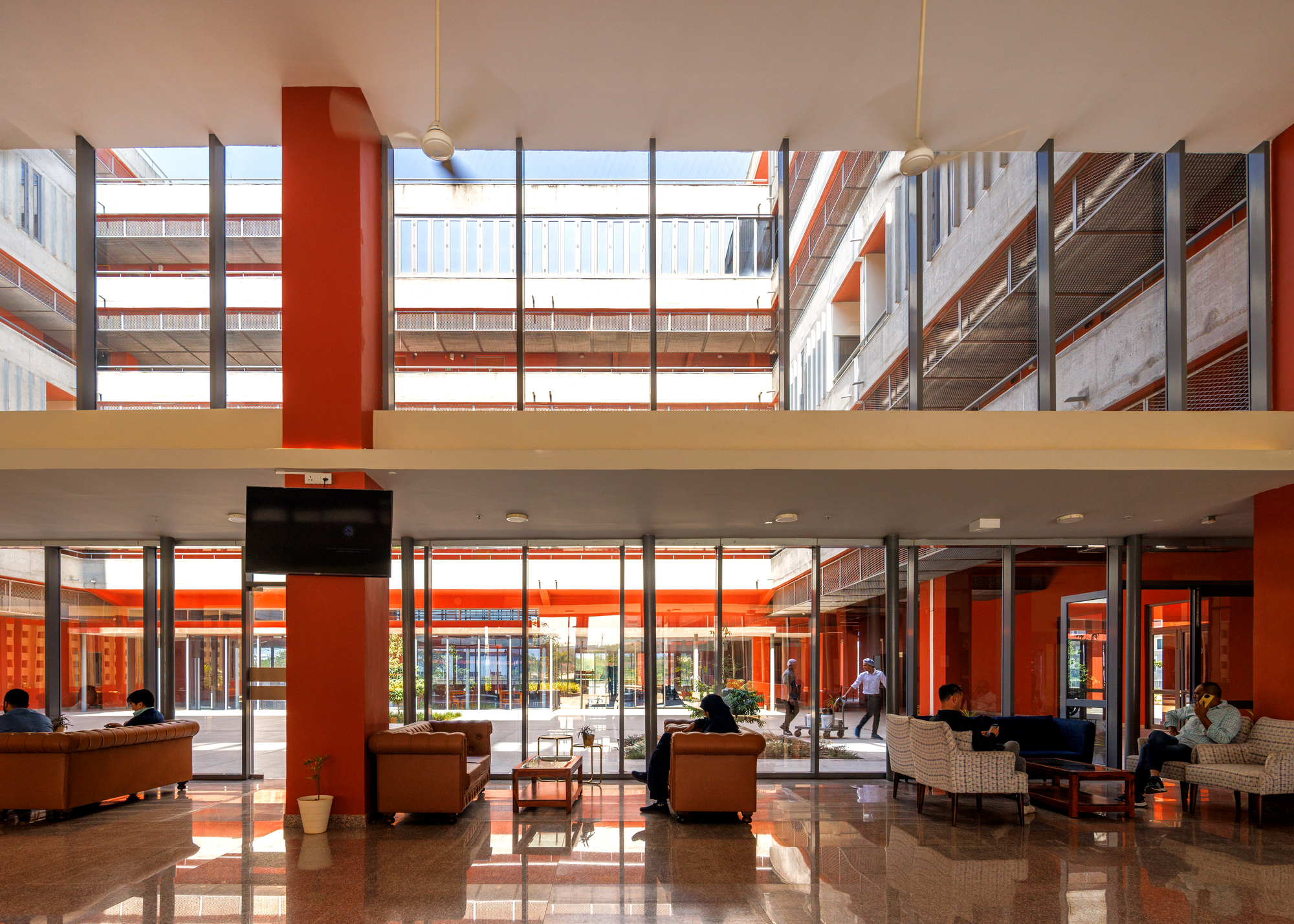 Double-height lobby with terrazzo floor, sofas and a view through to the courtyard