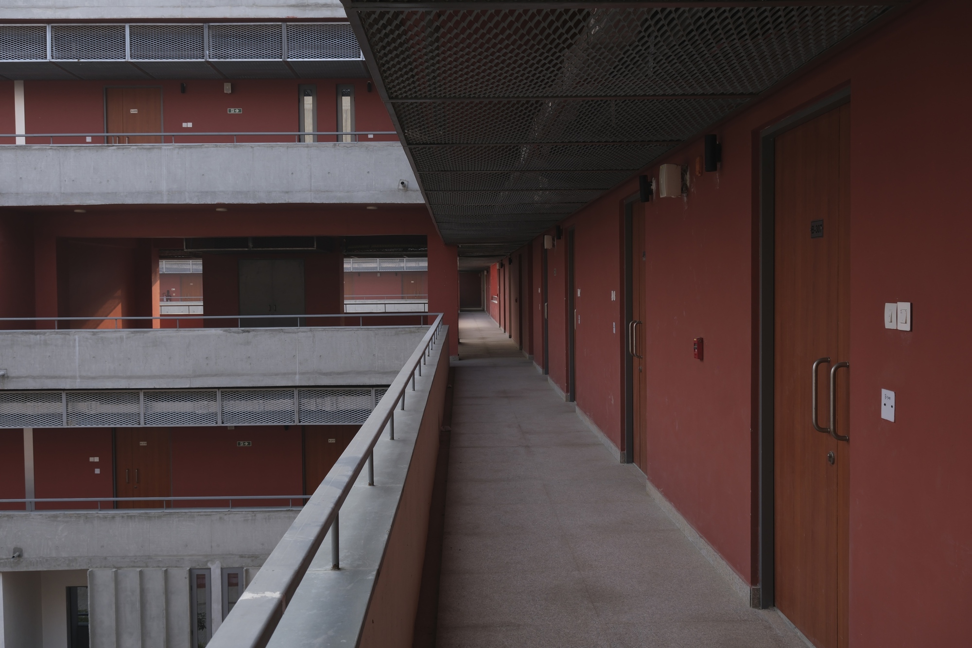 Internal access balcony at upper level with red walls and a steel mesh ceiling