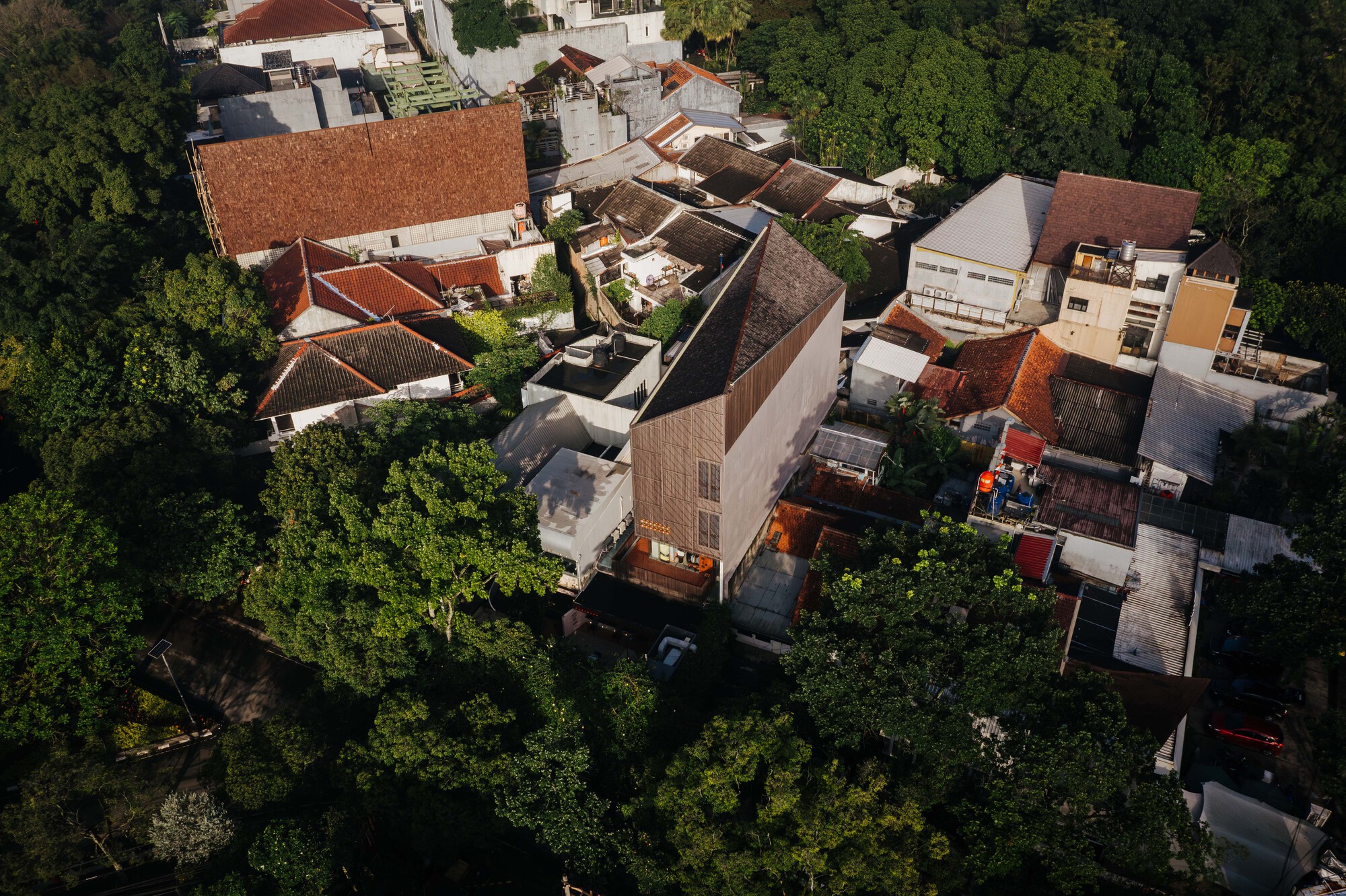 Aerial view of densely packed terracotta tile roofs and courtyards surrounded by mature trees