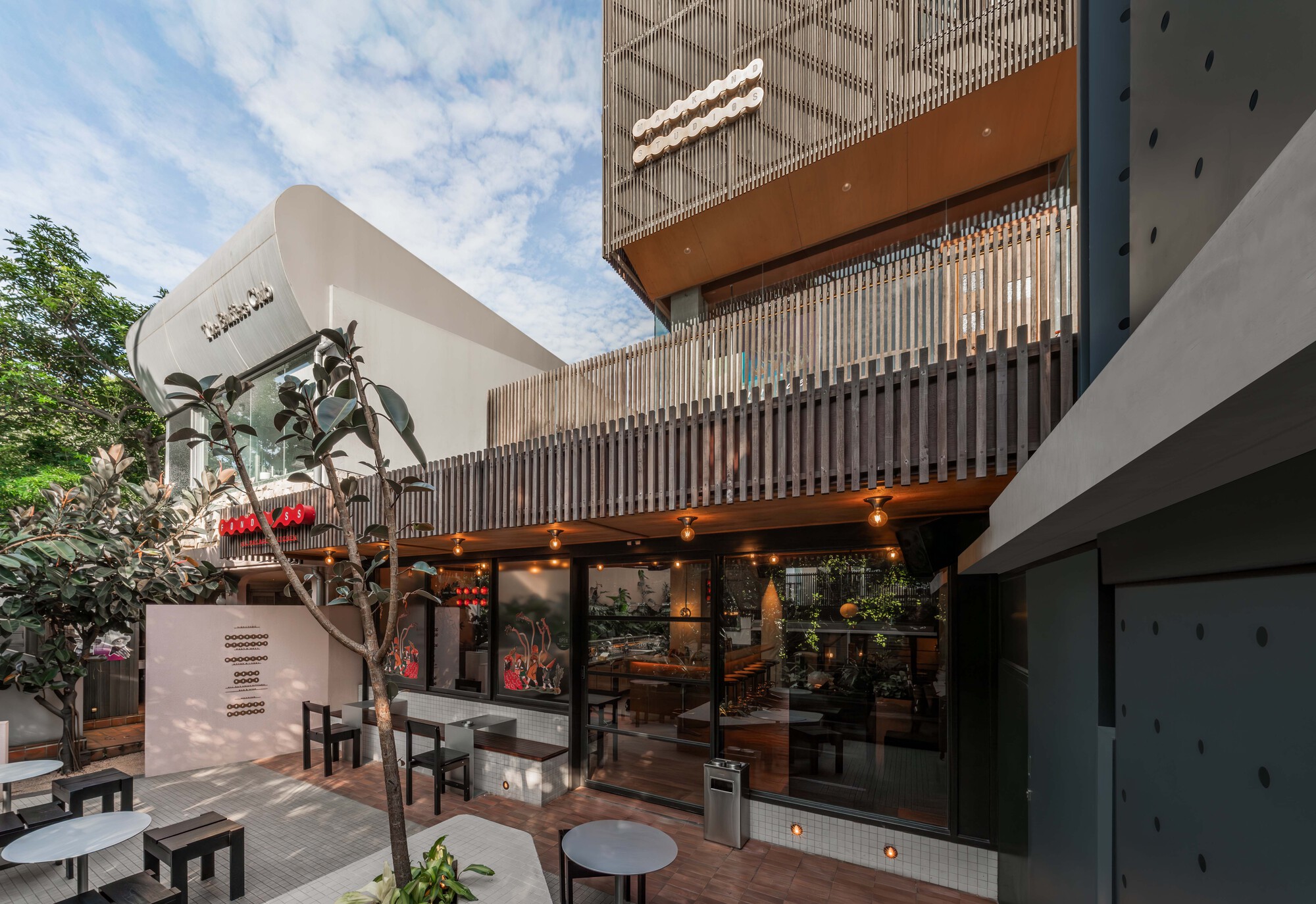 Courtyard with outdoor seating, planted tree and facade with timber slat screens at daytime