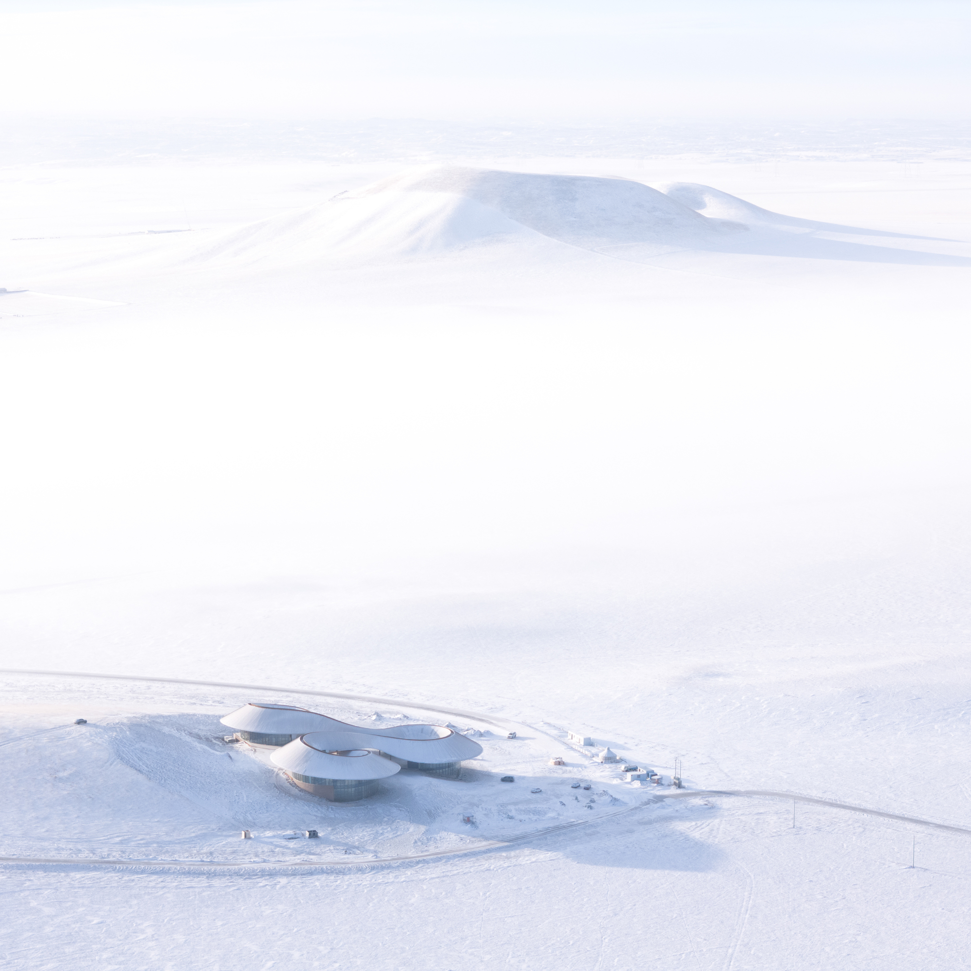 Distant aerial of the visitor center sitting in the snow with the extinct volcano cone behind
