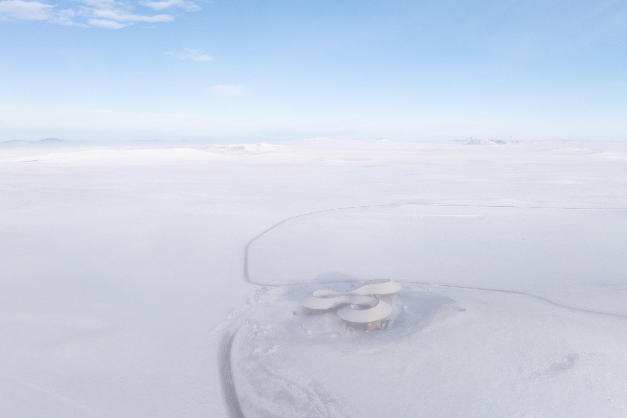 Drone view of the curving cloverleaf-shaped roof in a vast snowfield