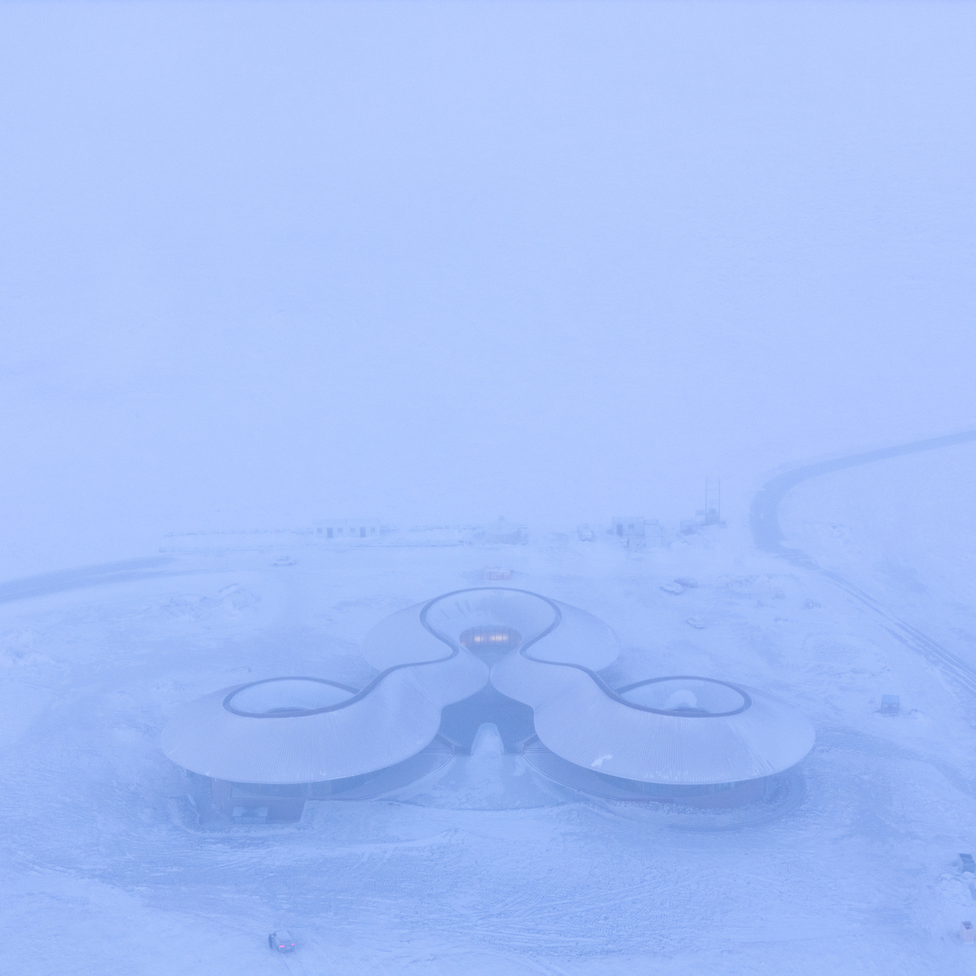Top-down view of the three-lobed roof in heavy snow and mist