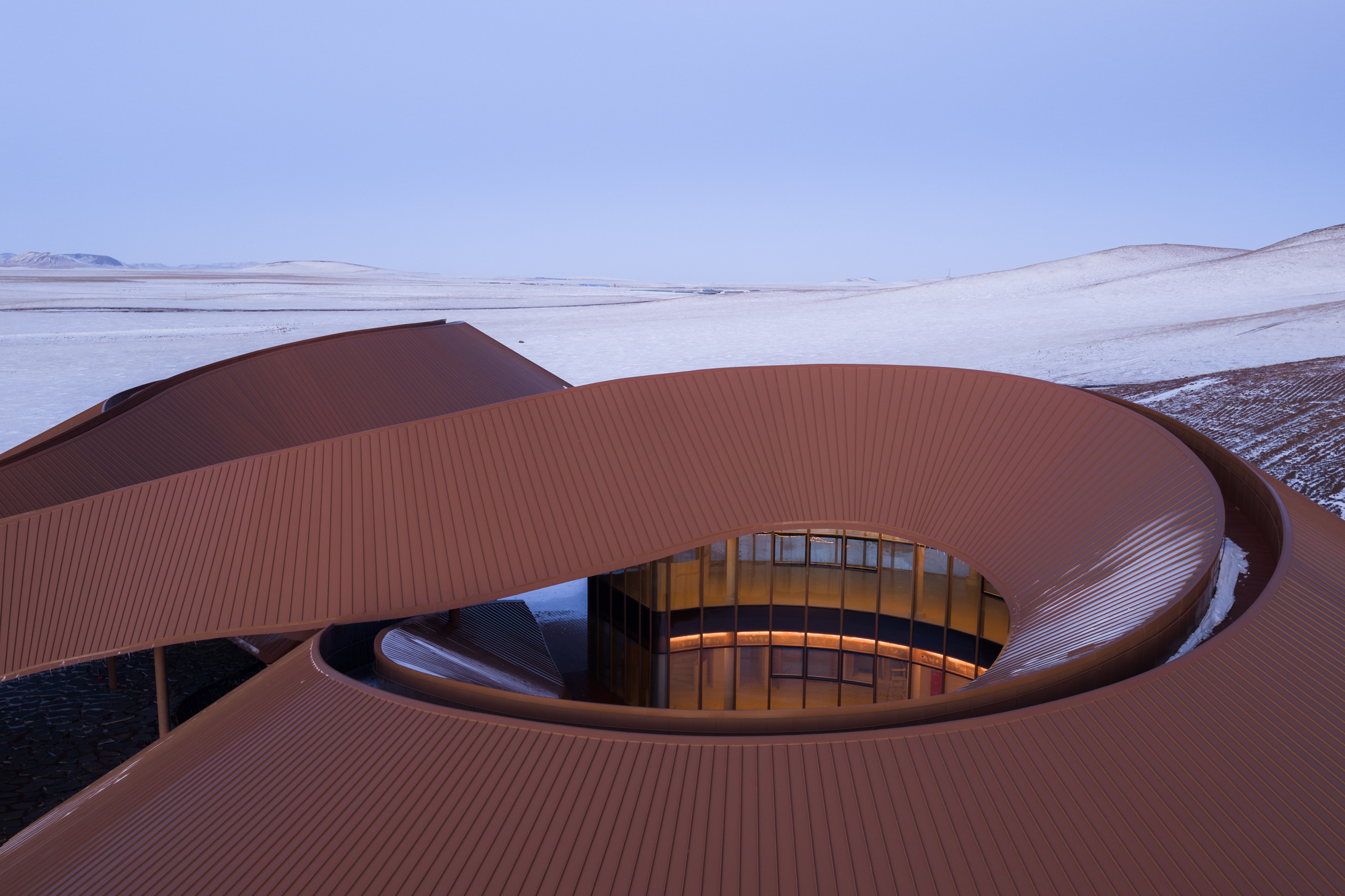 Detail of the curving roof and one of the circular skylight openings glowing yellow