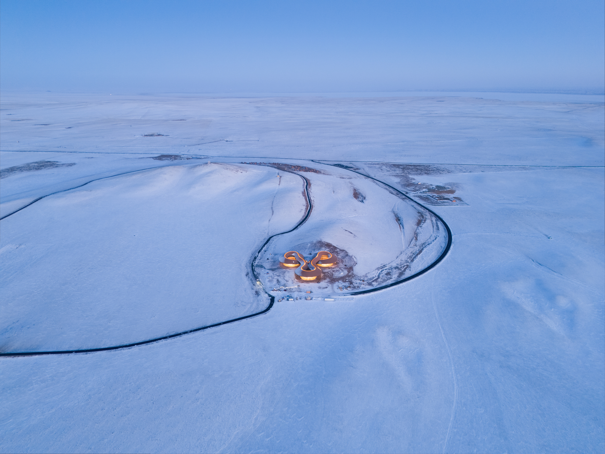 Aerial of the building set inside the C-shaped curve of the extinct volcano at dusk
