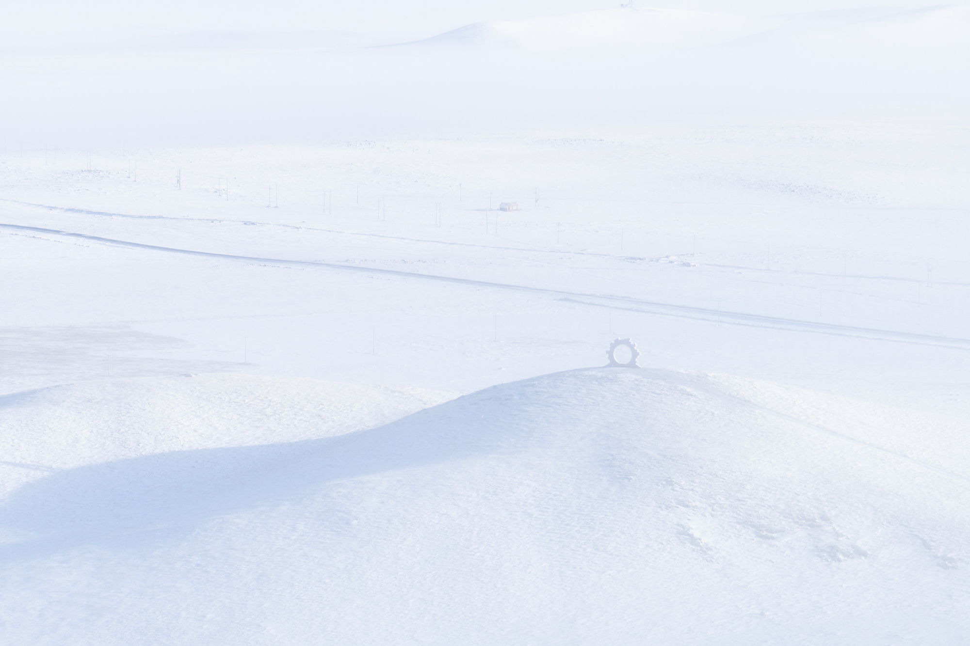 Distant horizon view of a tiny circular structure sitting on a low rise in the snow