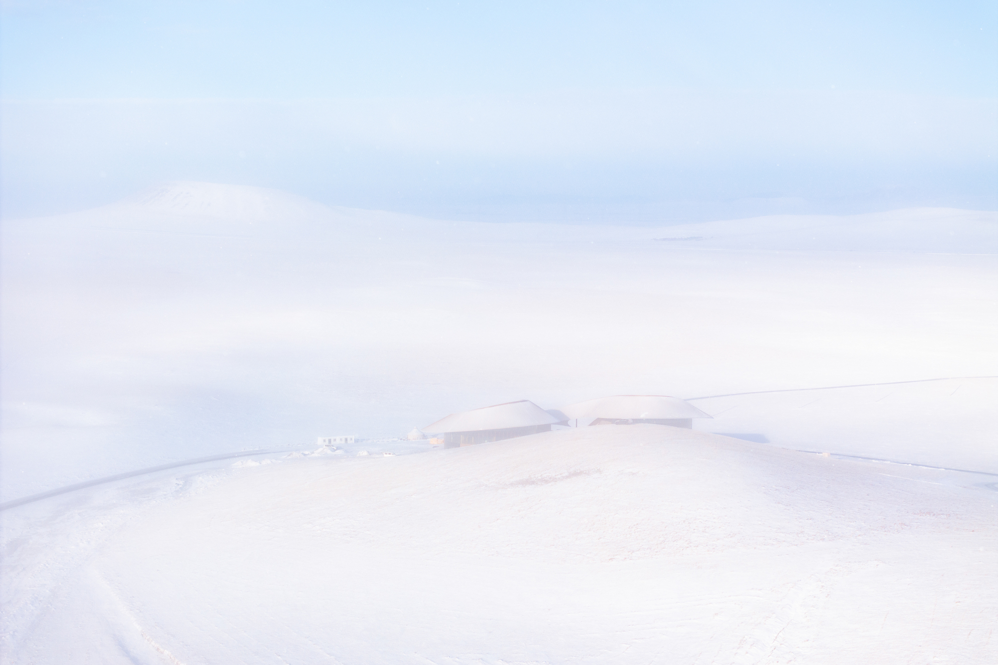Almost-monochrome view of the building barely visible in the snowfield