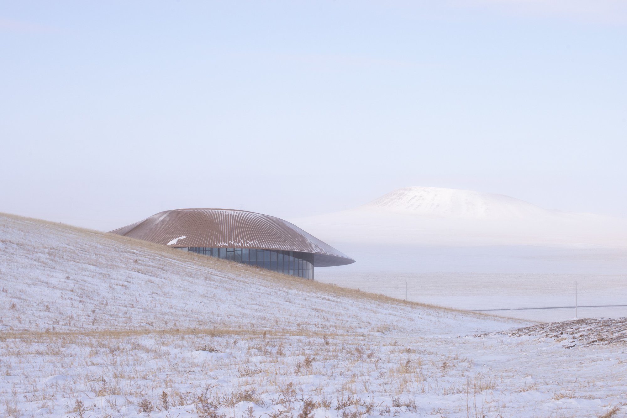 View across the steppe with the building on a low ridge and the volcano cone in the distance