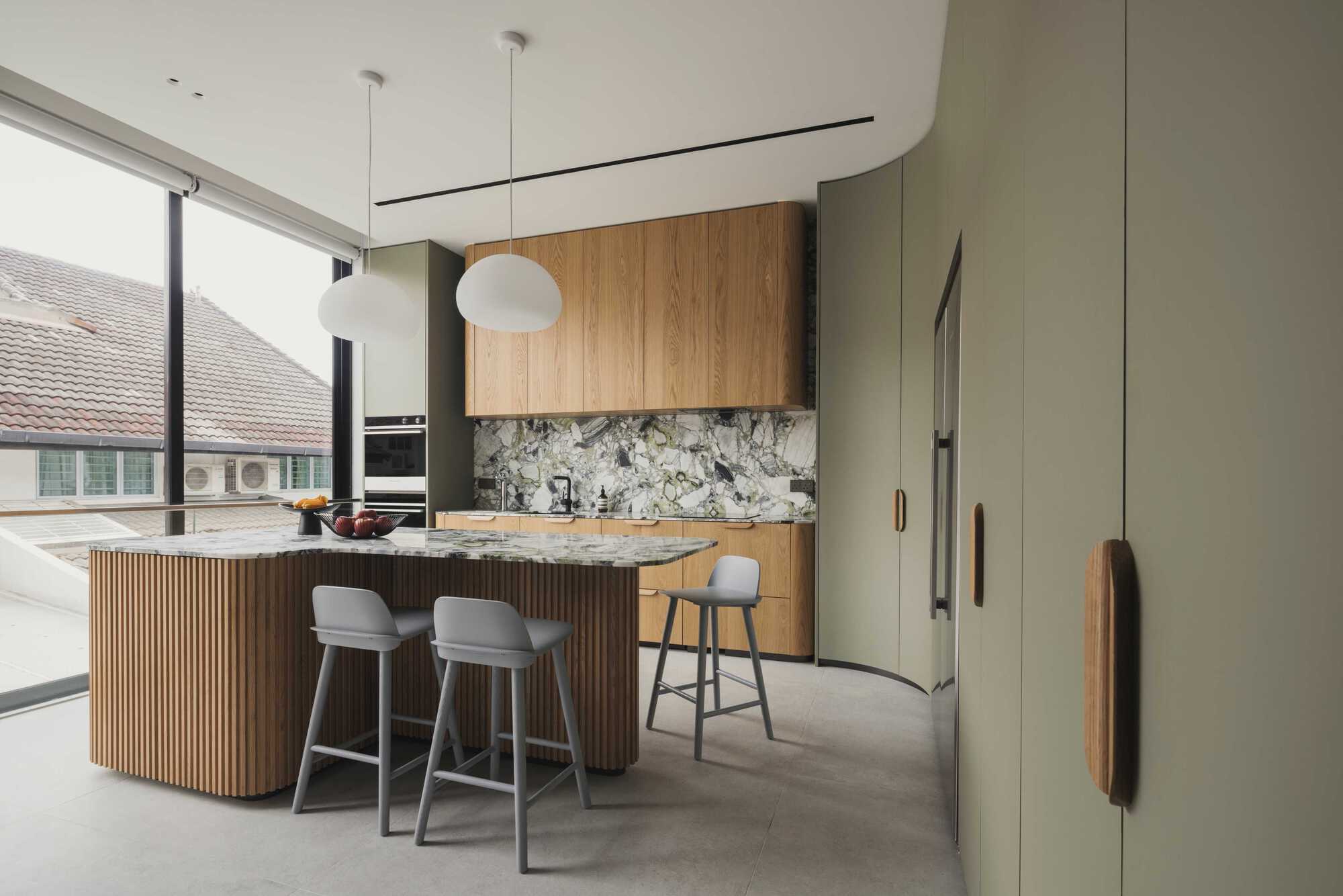 Kitchen with curved ribbed timber island and marbled stone backsplash beneath white dome pendants