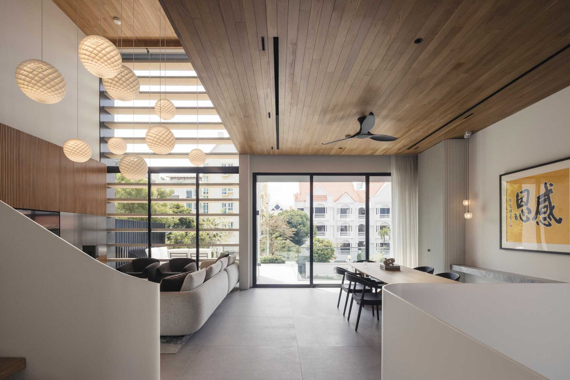 Double-height living space with timber ceiling, horizontal louvered screens and woven pendant lights