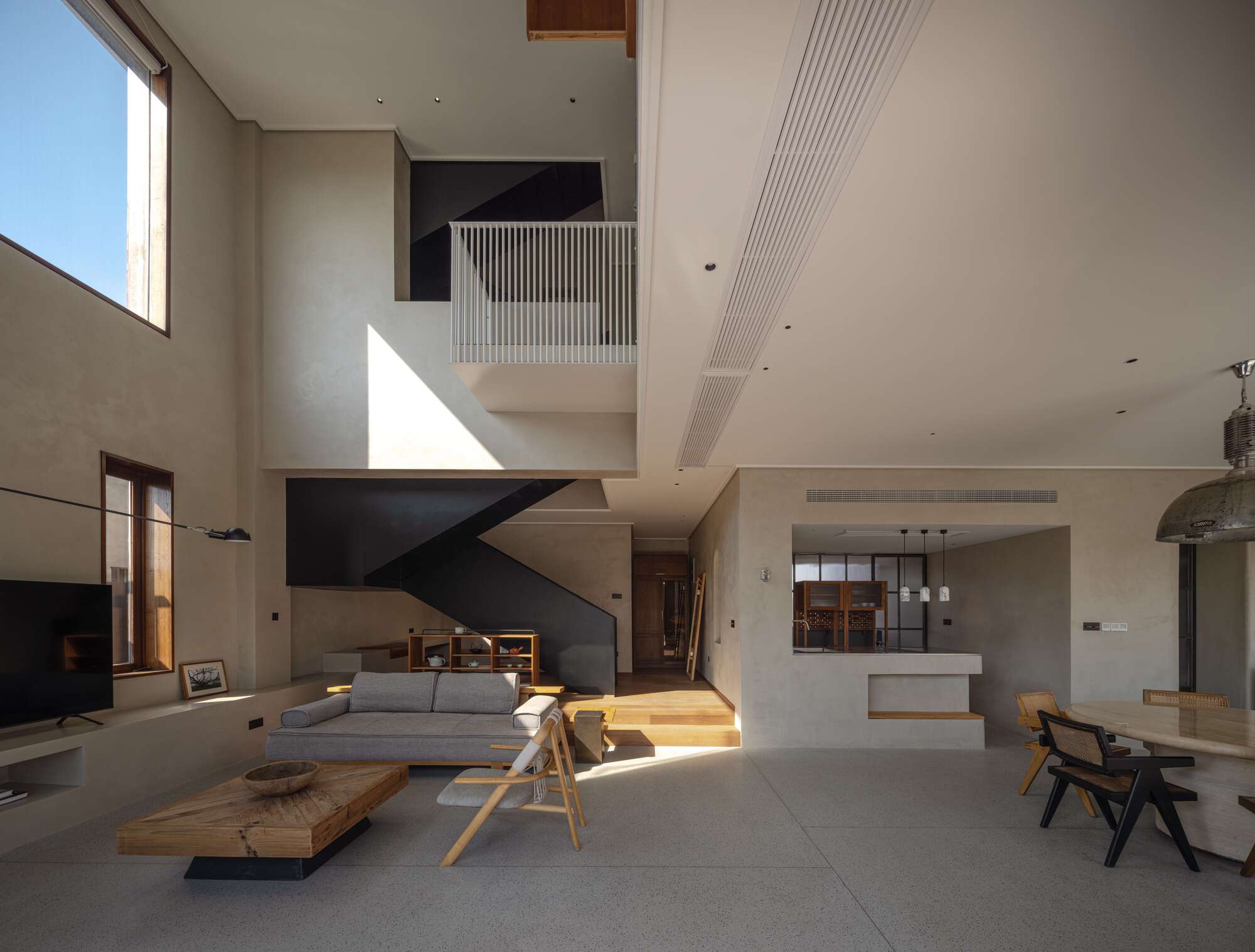 Double-height living space with black steel stair and sunlight streaming through high clerestory window