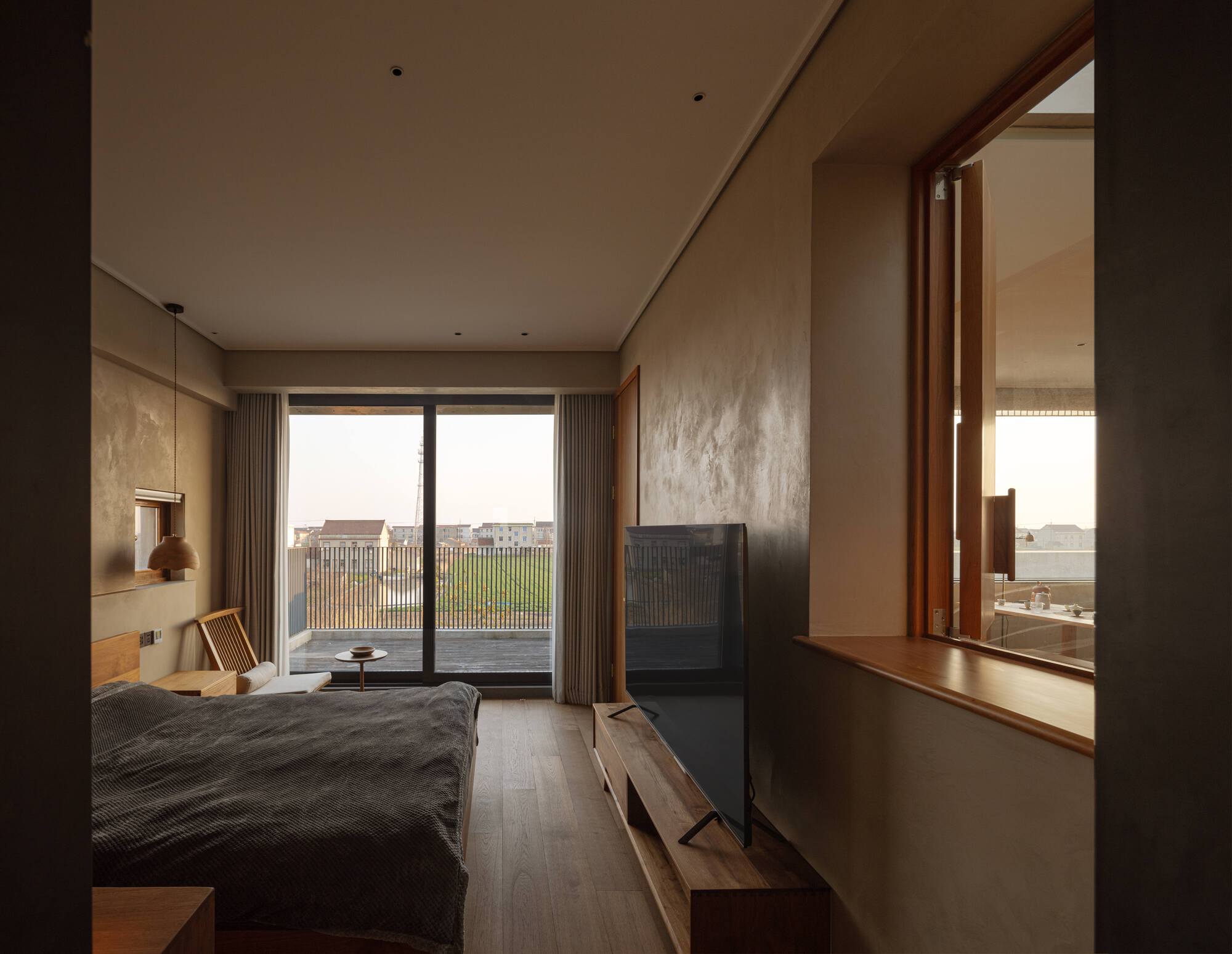 Bedroom with timber-framed window alcove overlooking fields and an ensuite bathroom beyond