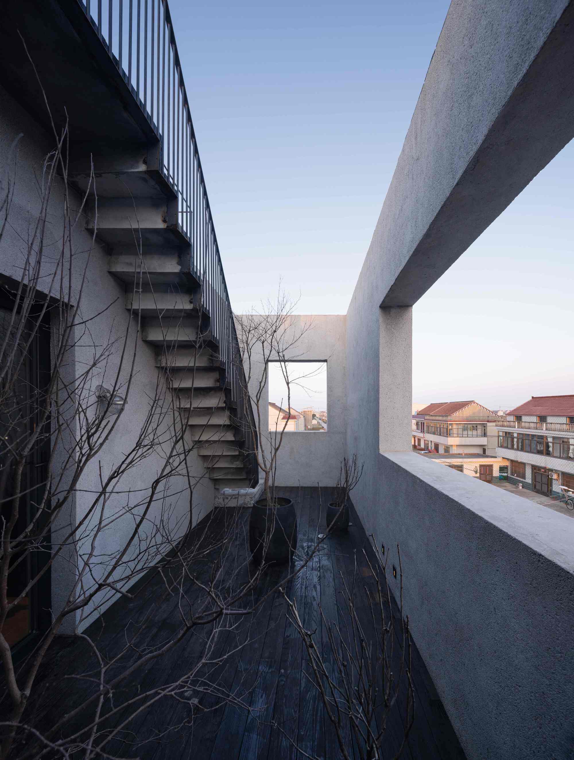Exterior steel staircase alongside corrugated metal cladding and bare winter vines at dusk