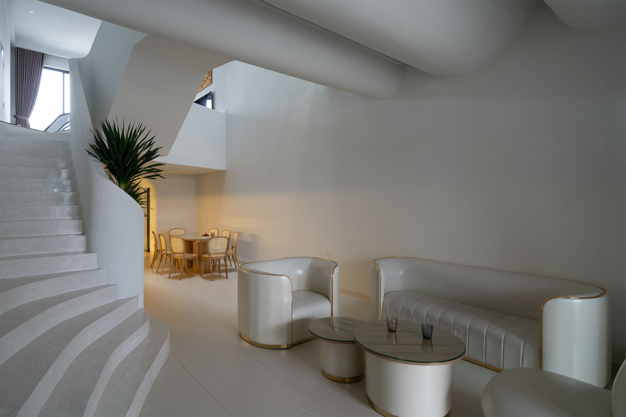 Interior view of the flowing white staircase with dining area and sculptural ceiling forms
