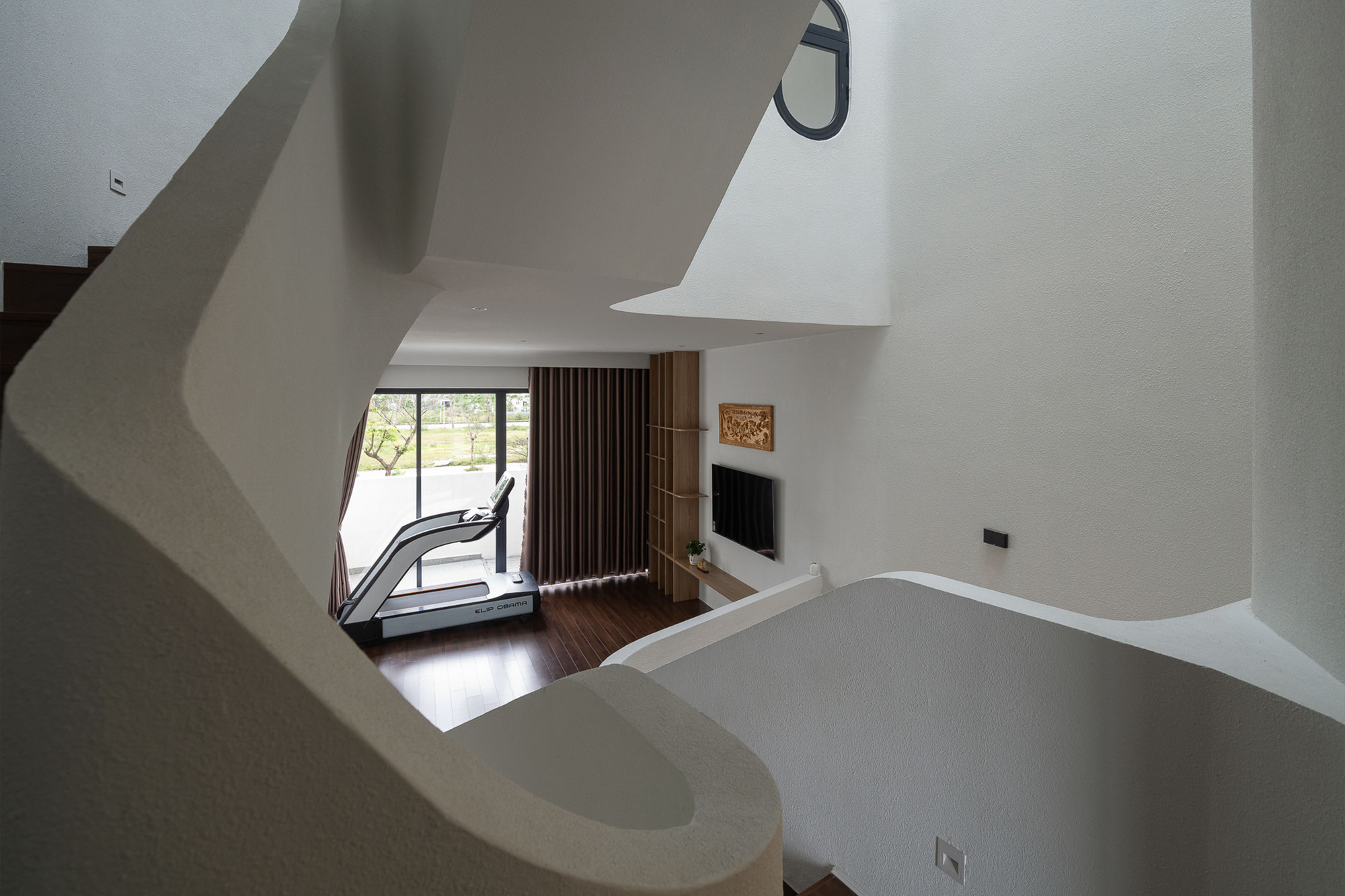 View down the curved stairwell to living space with vertical timber slat screen