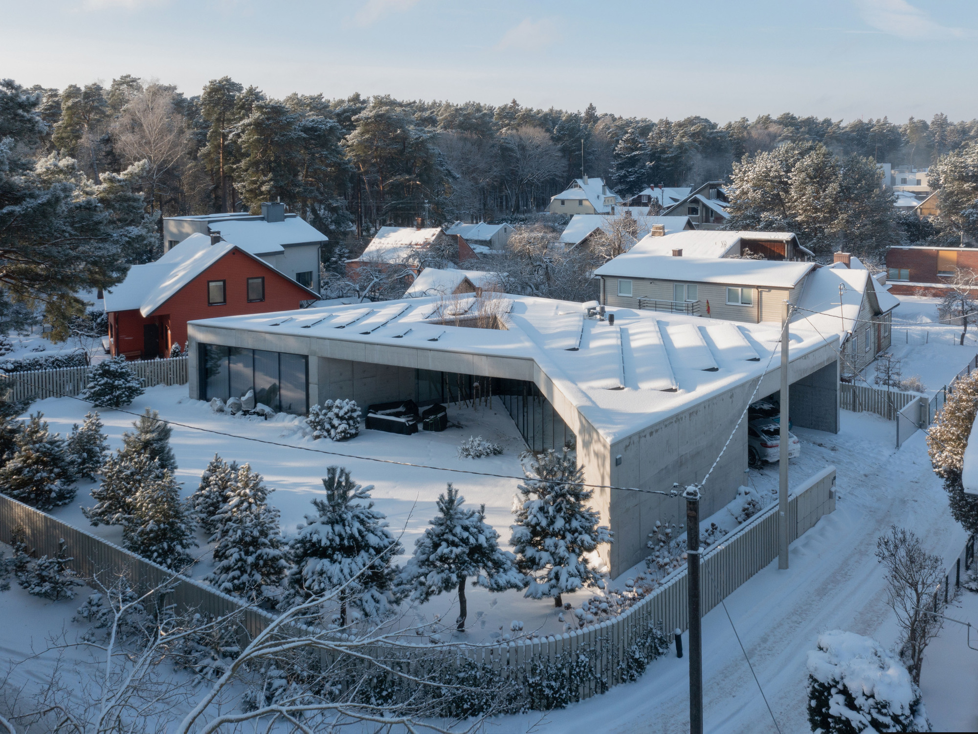 Aerial view of the triangular roof geometry nestled in a snow-covered residential neighborhood with pine trees