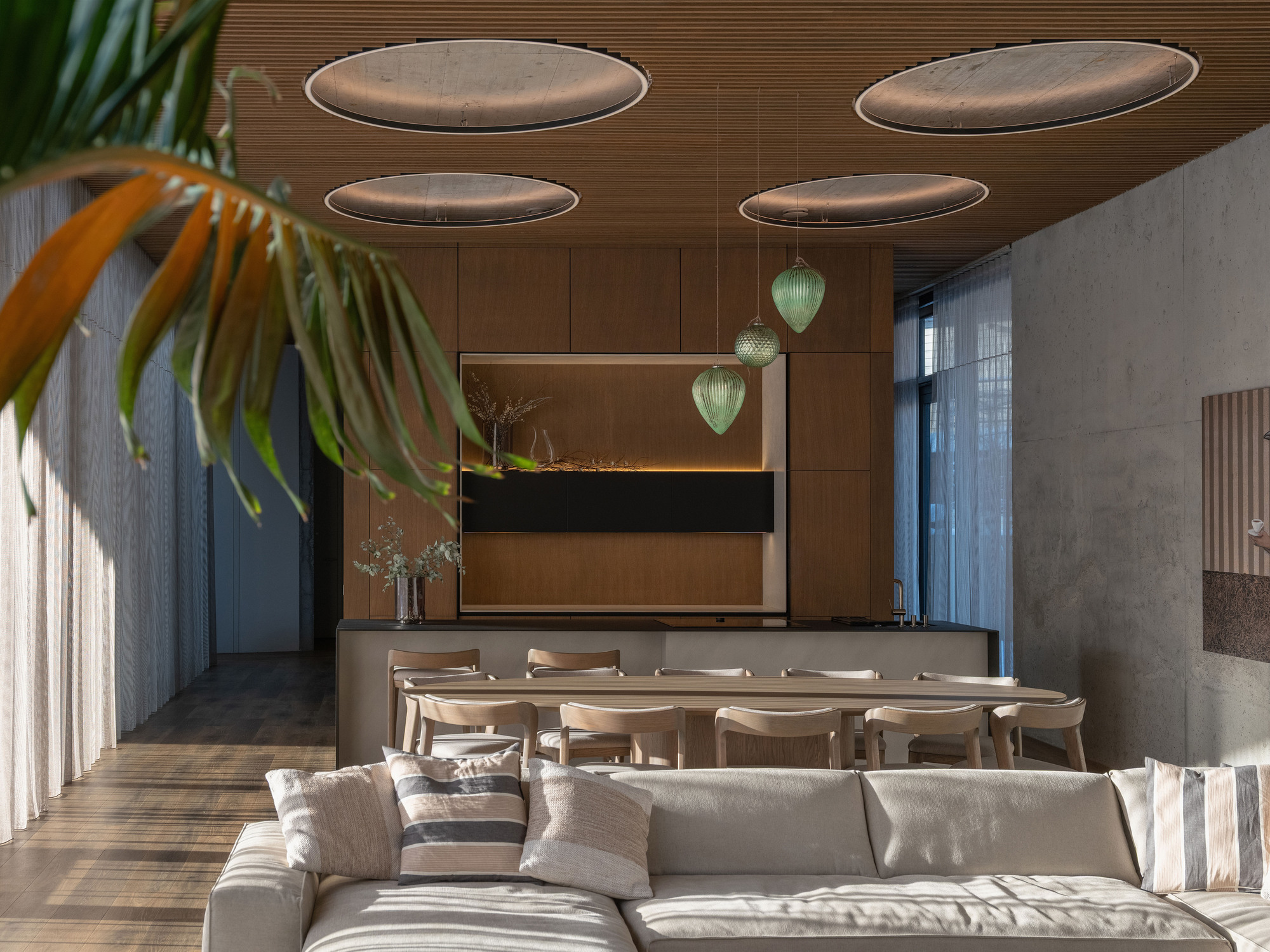 Combined dining and living area with circular acoustic panels suspended below a timber ceiling